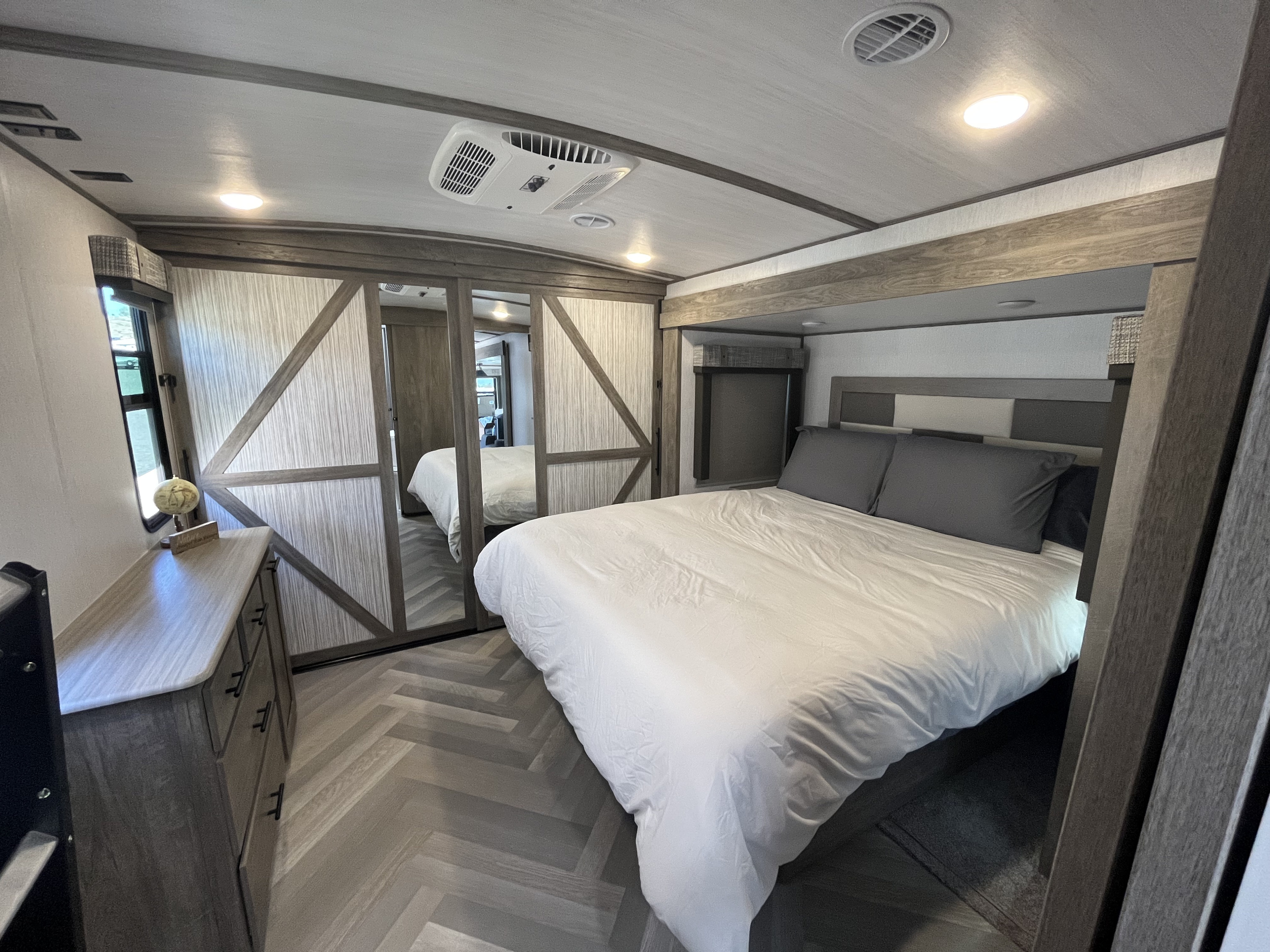 Spacious RV rental bedroom with modern decor, queen bed, mirrored closet, and herringbone flooring.. Forest River Salem Hemisphere 2022