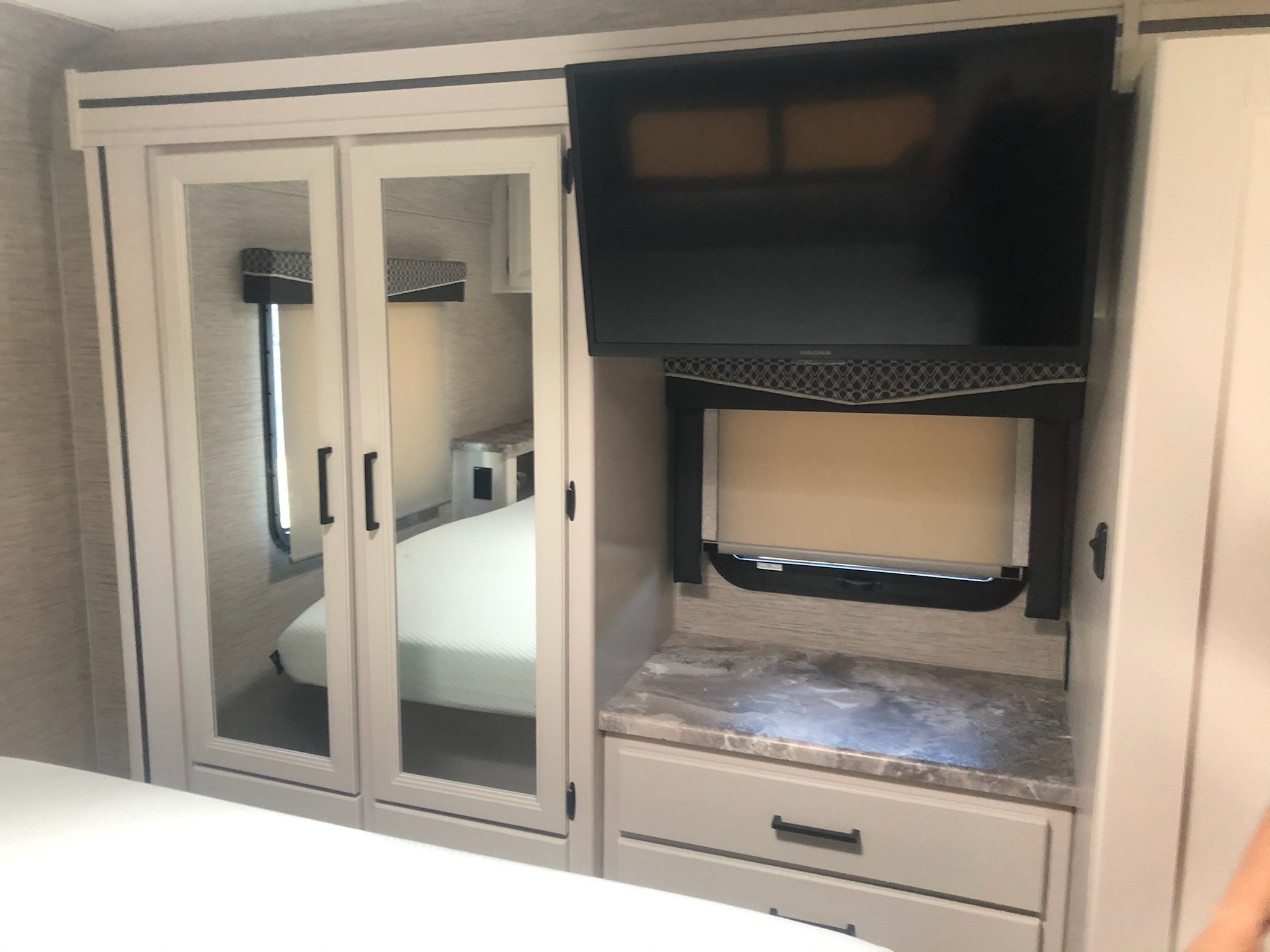 Modern RV rental bedroom interior with mirrored closet, TV, and storage drawers. Clean and functional space.. Thor Motor Coach Chateau 2023