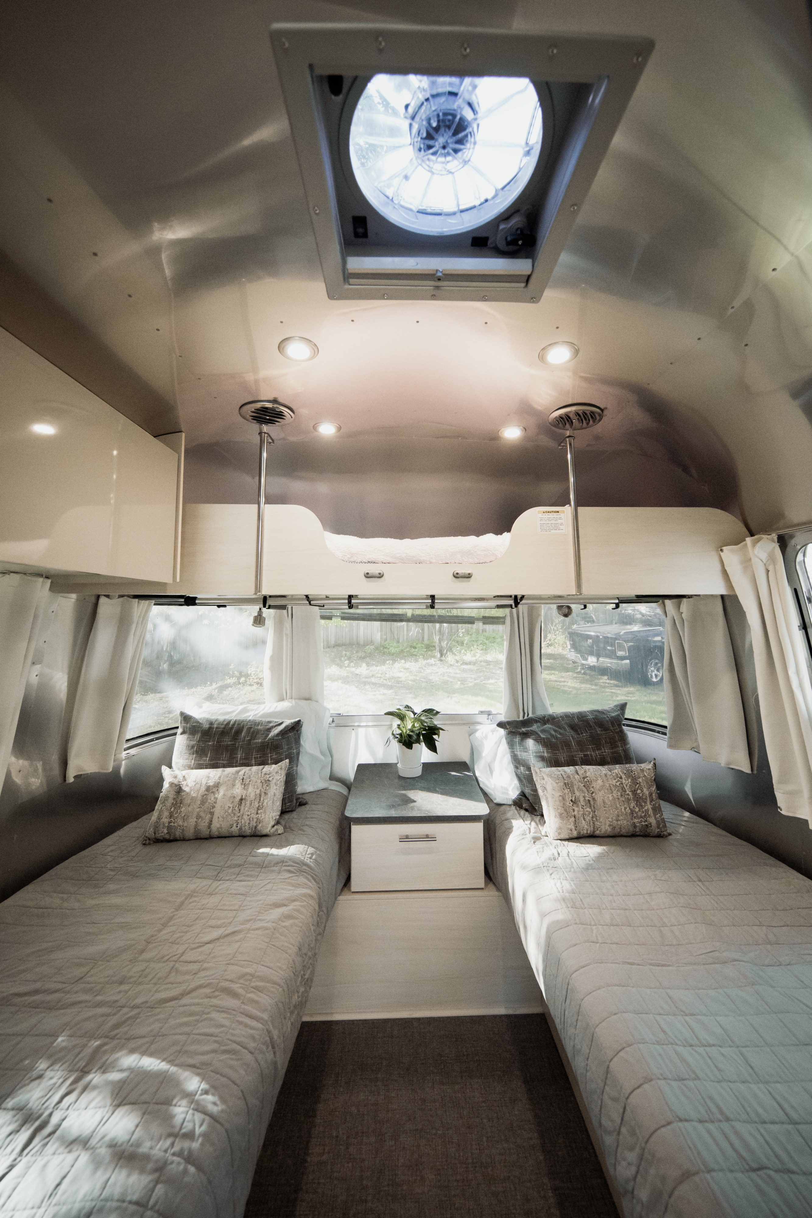 Spacious RV rental interior featuring cozy twin beds, an overhead bunk, and bright natural light. Ideal for a travel adventure.. Airstream Flying Cloud 2021