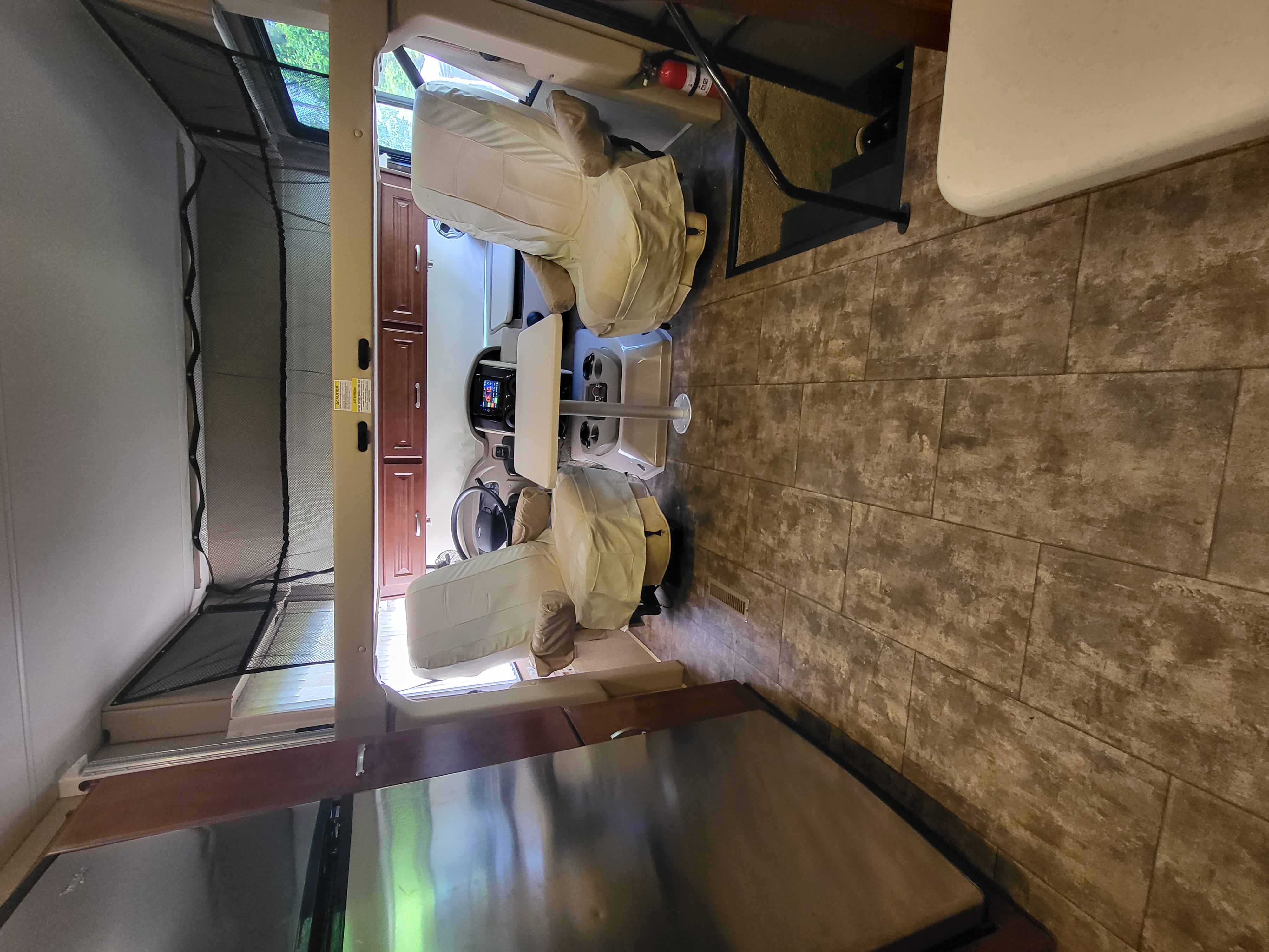 Inside an RV rental: the driver's cockpit with covered seats, overhead bunk, and durable flooring for your journey.. Thor Challenger 2015