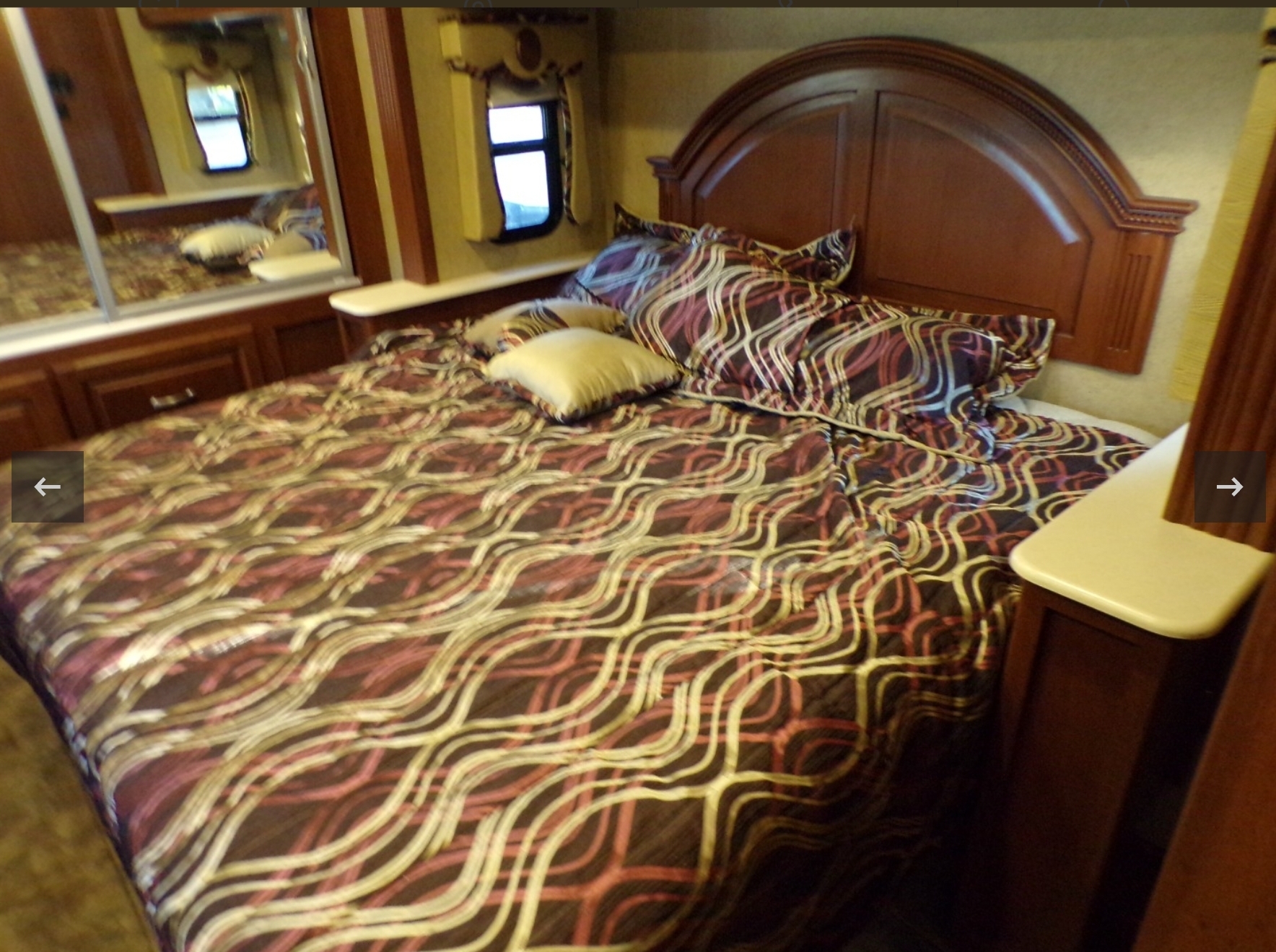 RV rental bedroom: A comfortable queen bed with a unique patterned comforter, wood headboard, and built-in mirrored closet.. Thor Challenger 2015