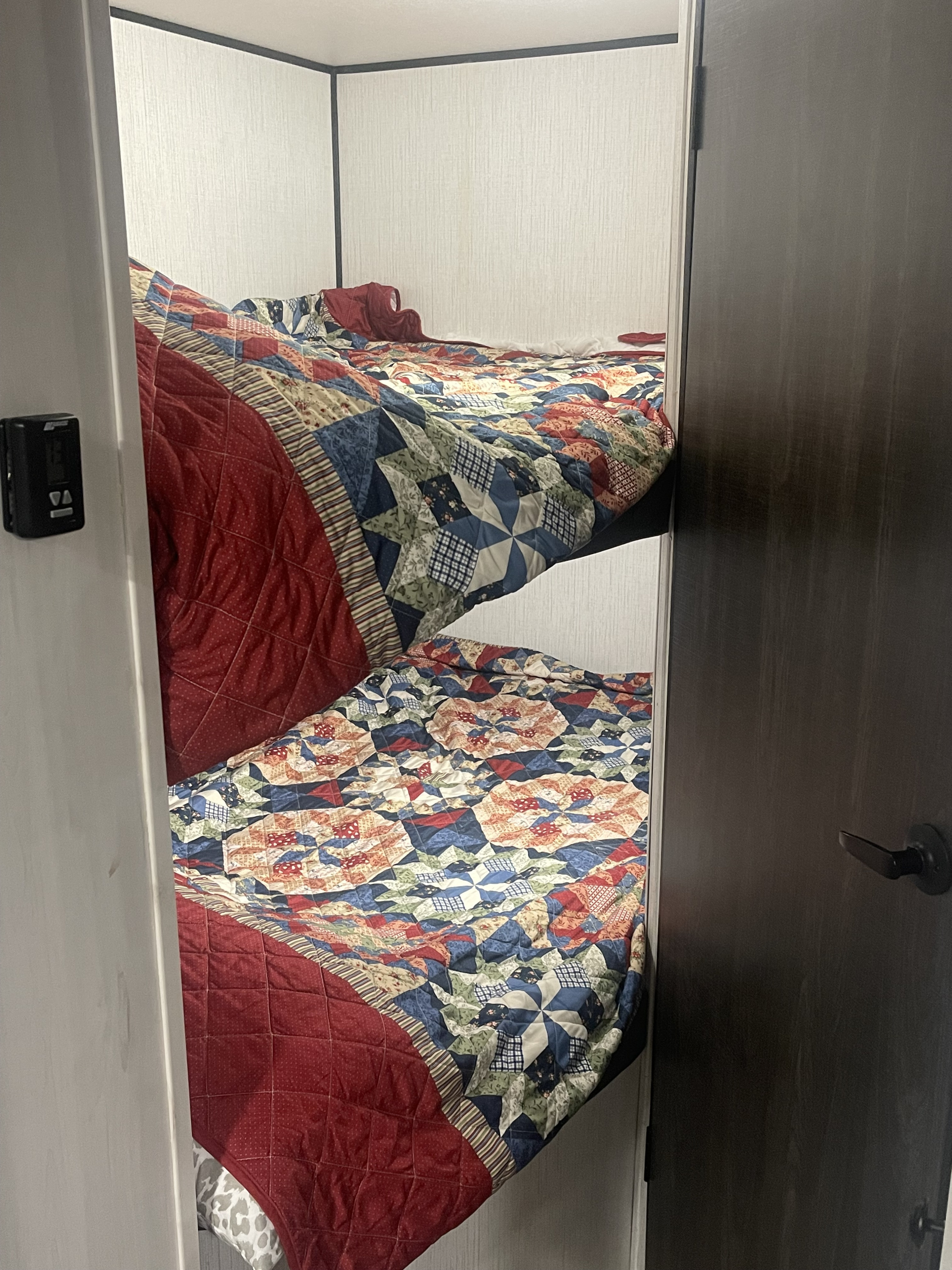 RV rental bedroom featuring cozy bunk beds with colorful patchwork quilts. Ideal for compact lodging.. Heartland RVs Trail Runner 2022