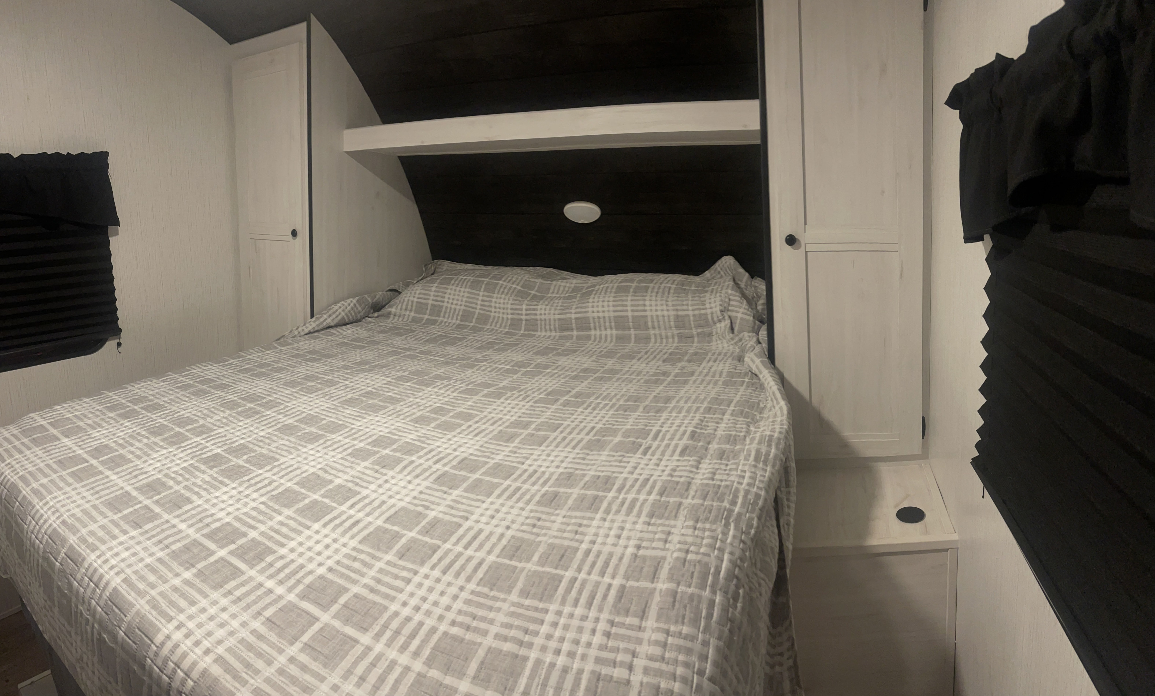 Cozy RV rental bedroom with plaid bed, cabinets, and window shades.. Heartland RVs Trail Runner 2022