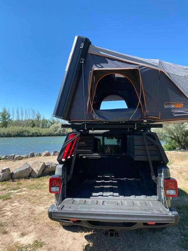 Alternative RV rental: Pickup truck with an open Roofnest rooftop tent, parked by a scenic river, ready for camping.. Other Other 2021