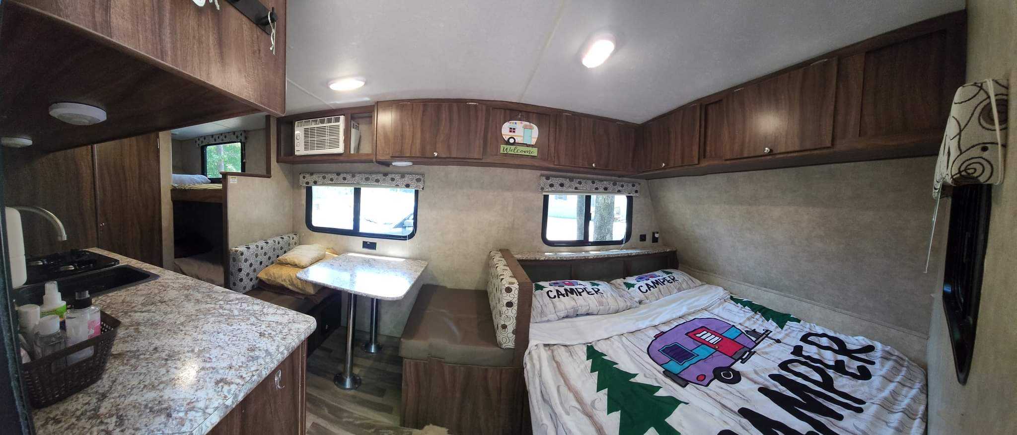 Inside this RV rental: a functional kitchen, dining area, a main bed with camper-themed bedding, and bunk beds in the rear.. Clipper Cadet 2017