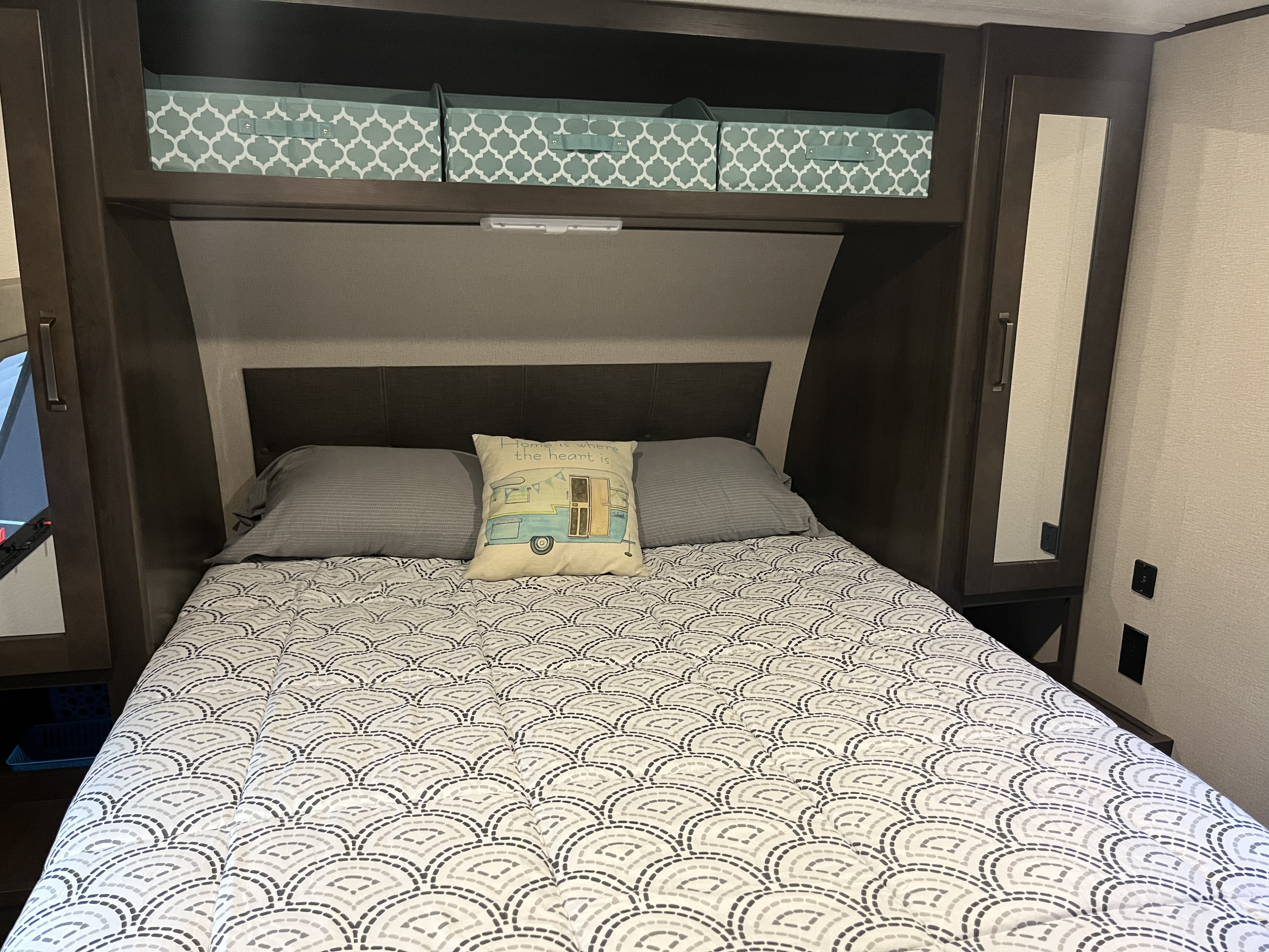 Inside an RV rental: a neat bedroom with gray and white patterned bedding, storage bins, and mirrored wardrobes. Comfortable sleeping area.. Grand Design Transcend Xplor 2020