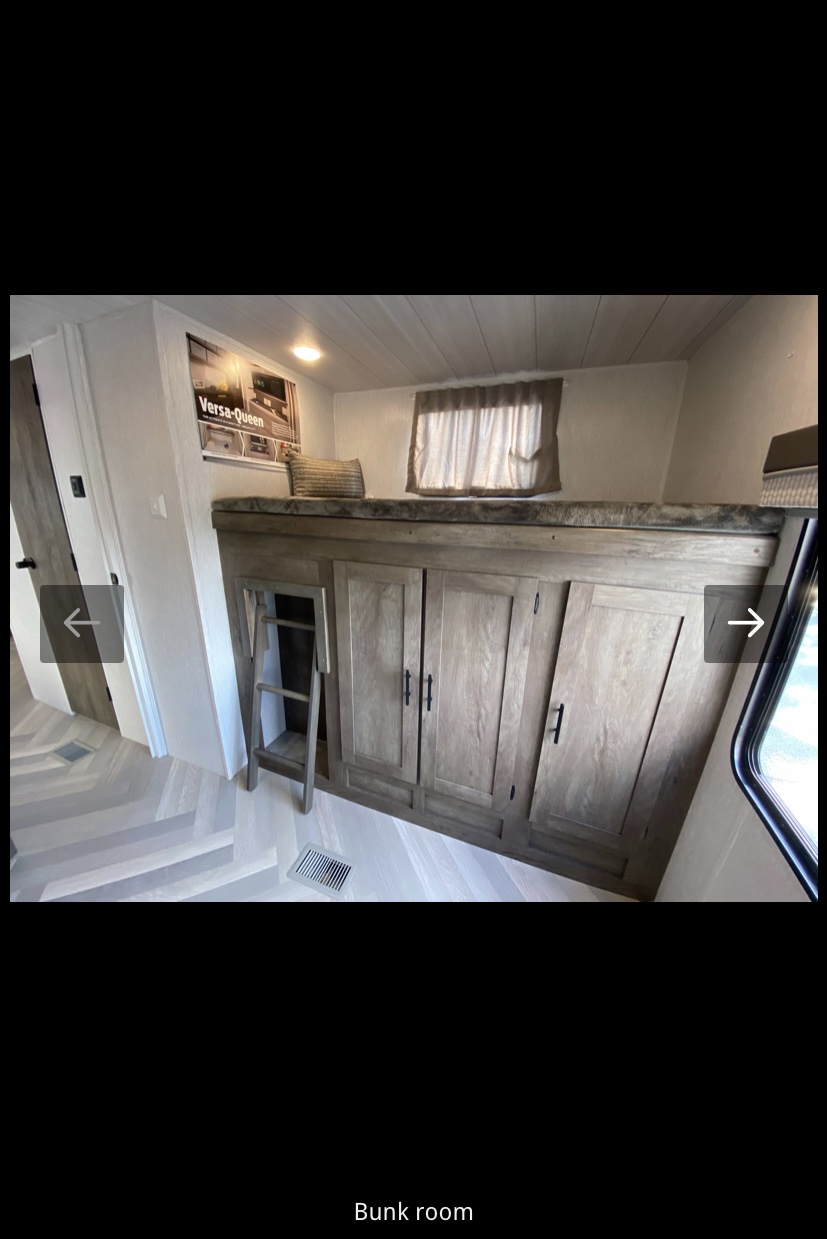 Spacious RV rental bunk room with top bunk, ladder, & ample storage cabinets. Light flooring & window complete the cozy interior.. Forest River Salem 2022