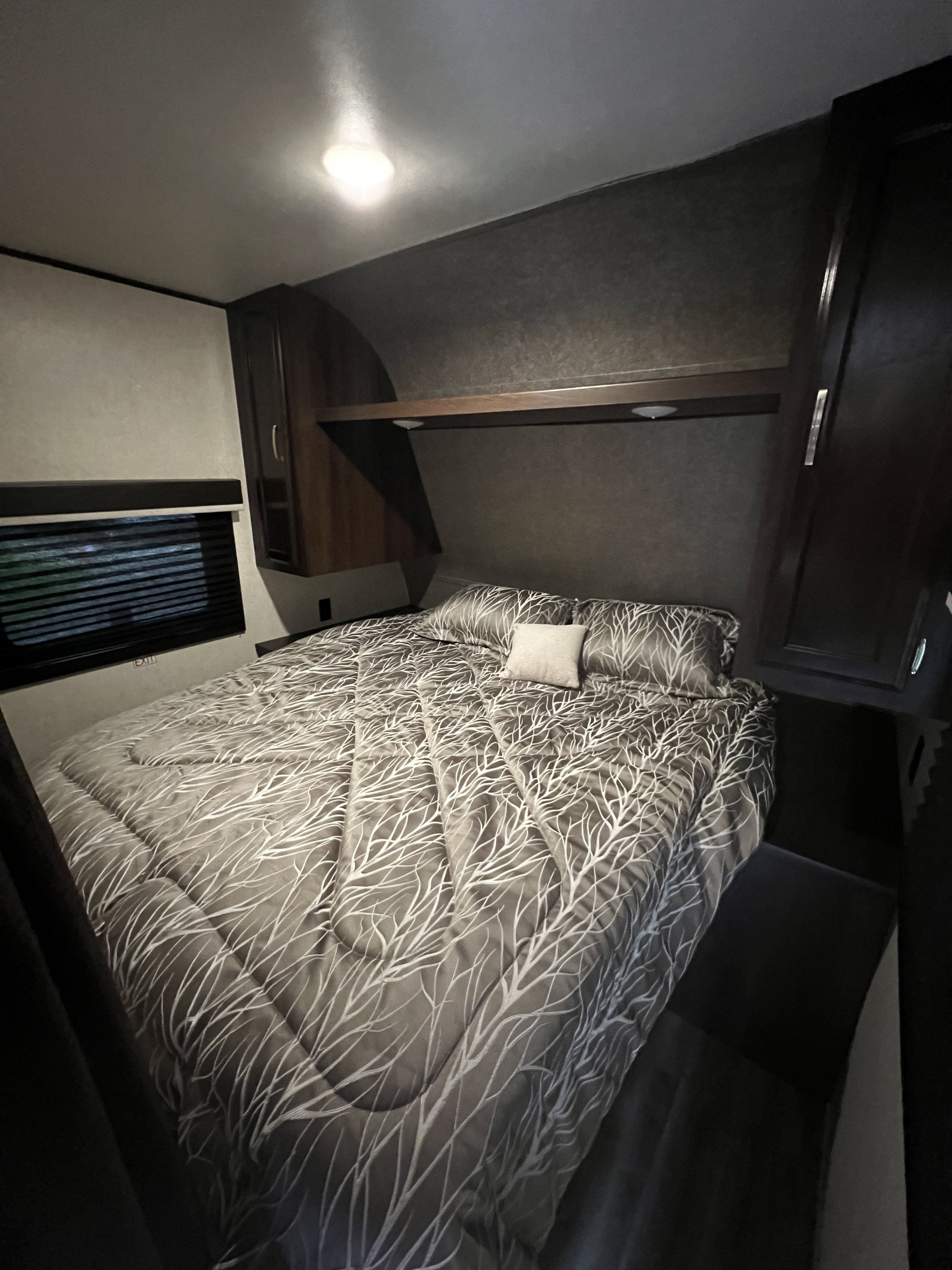Cozy RV rental bedroom with a full bed, patterned comforter, overhead storage, window blinds, and interior lighting.. Jayco Jay Flight 2020