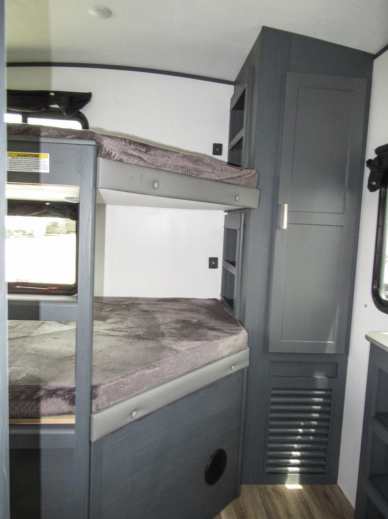 Inside this RV rental, dual bunk beds with plush grey covers provide comfortable sleeping, alongside built-in dark grey storage.. Keystone RV Bullet Ultra Lite 2022