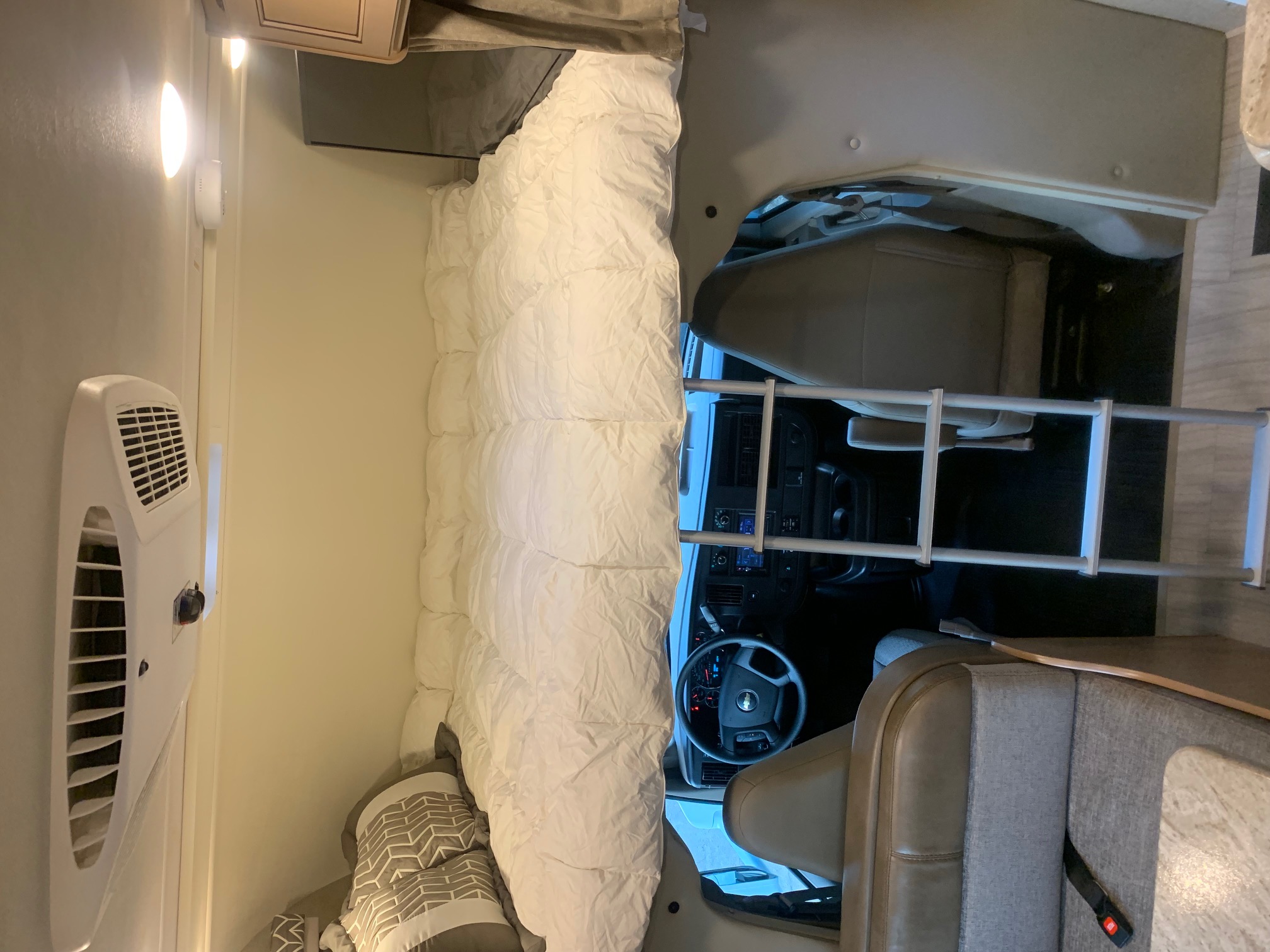 RV rental interior with a spacious bed over the cab, plus a ladder, cockpit, and dinette for travel.. Thor Daybreak 2020