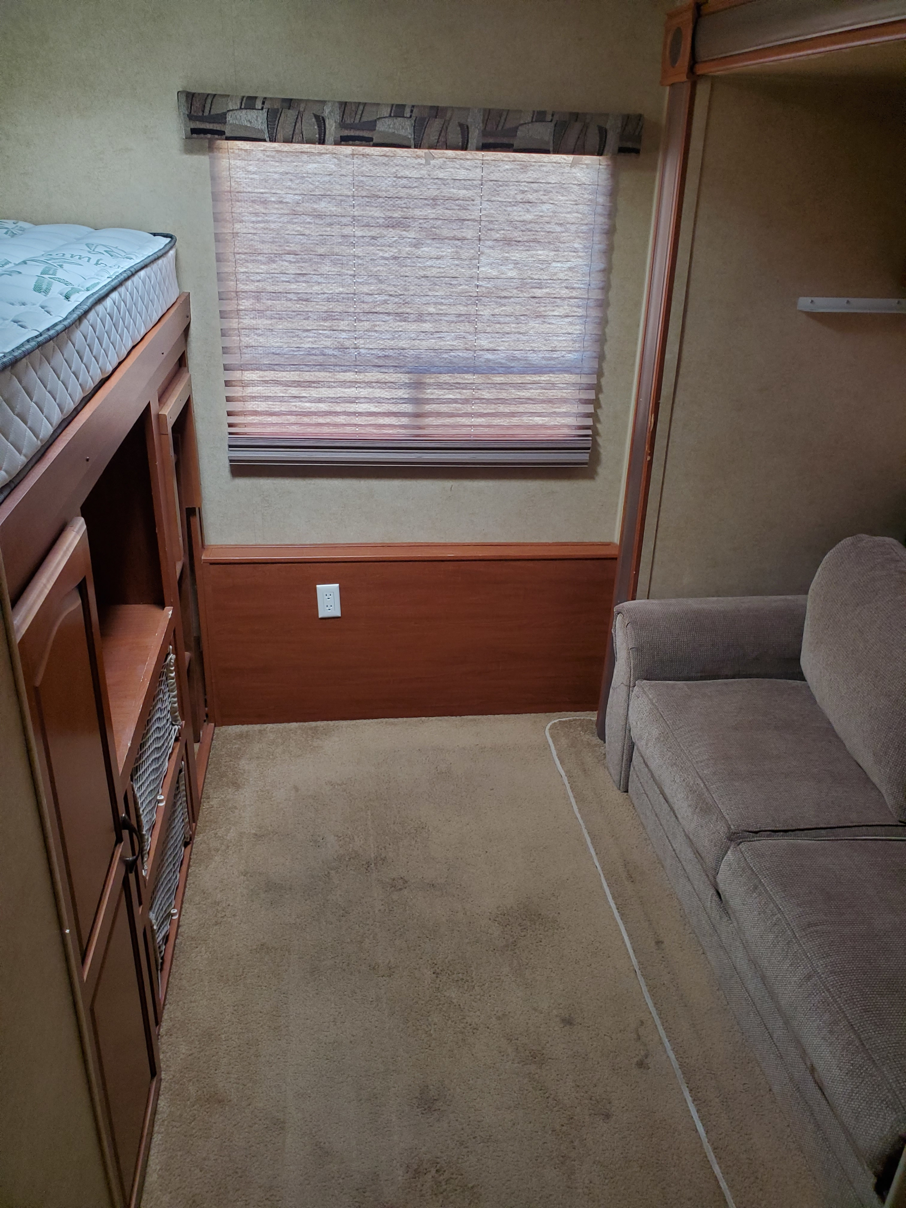 This RV rental interior features a bunk bed, sofa, window with blinds, and built-in storage, creating a functional living space.. Forest River Surveyor Select 2012