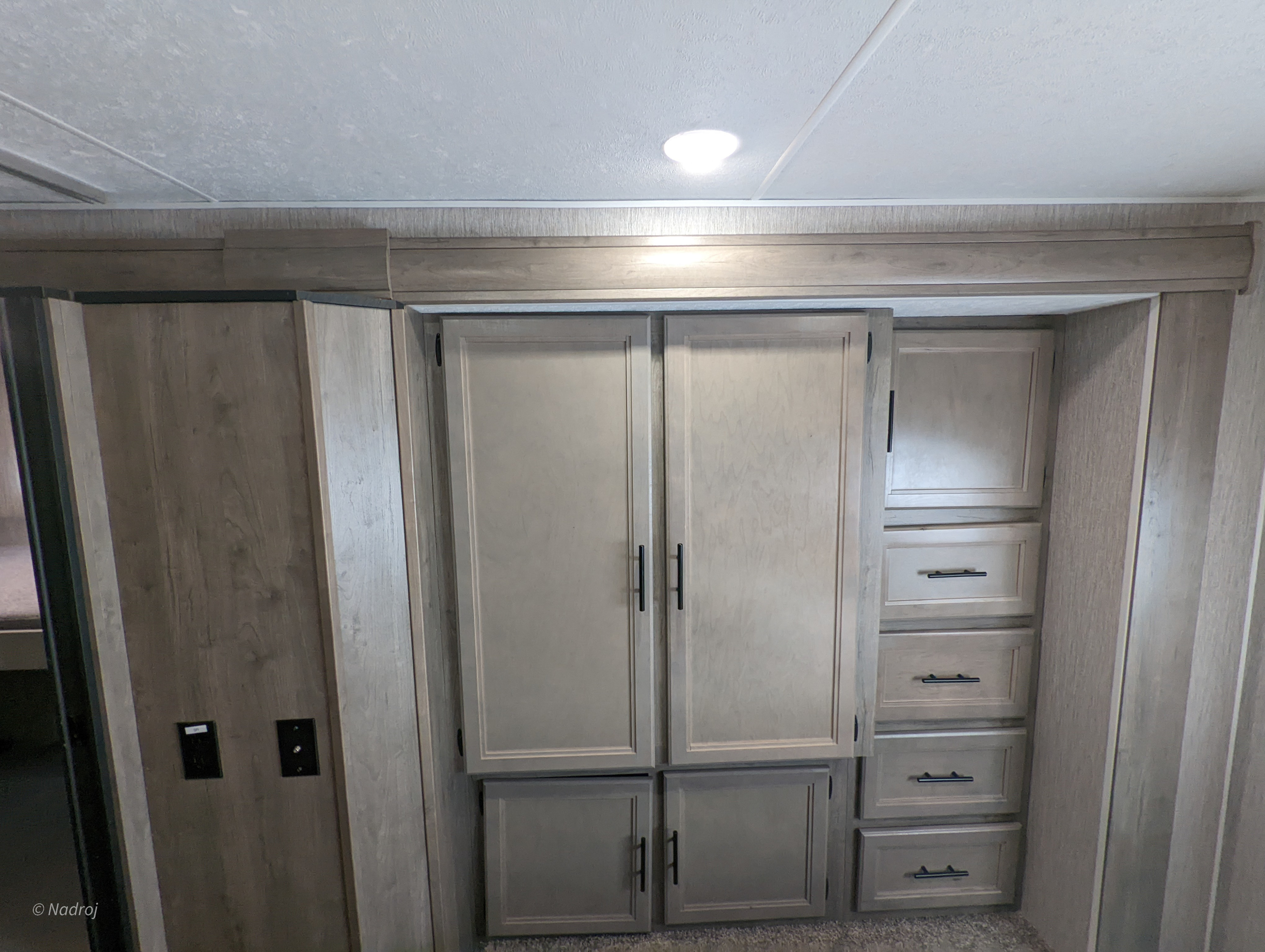 RV rental: Compact light wood cabinetry with black handles, including wardrobe, drawers, and ceiling light.. Forest River Coachmen Freelander Premier 2021