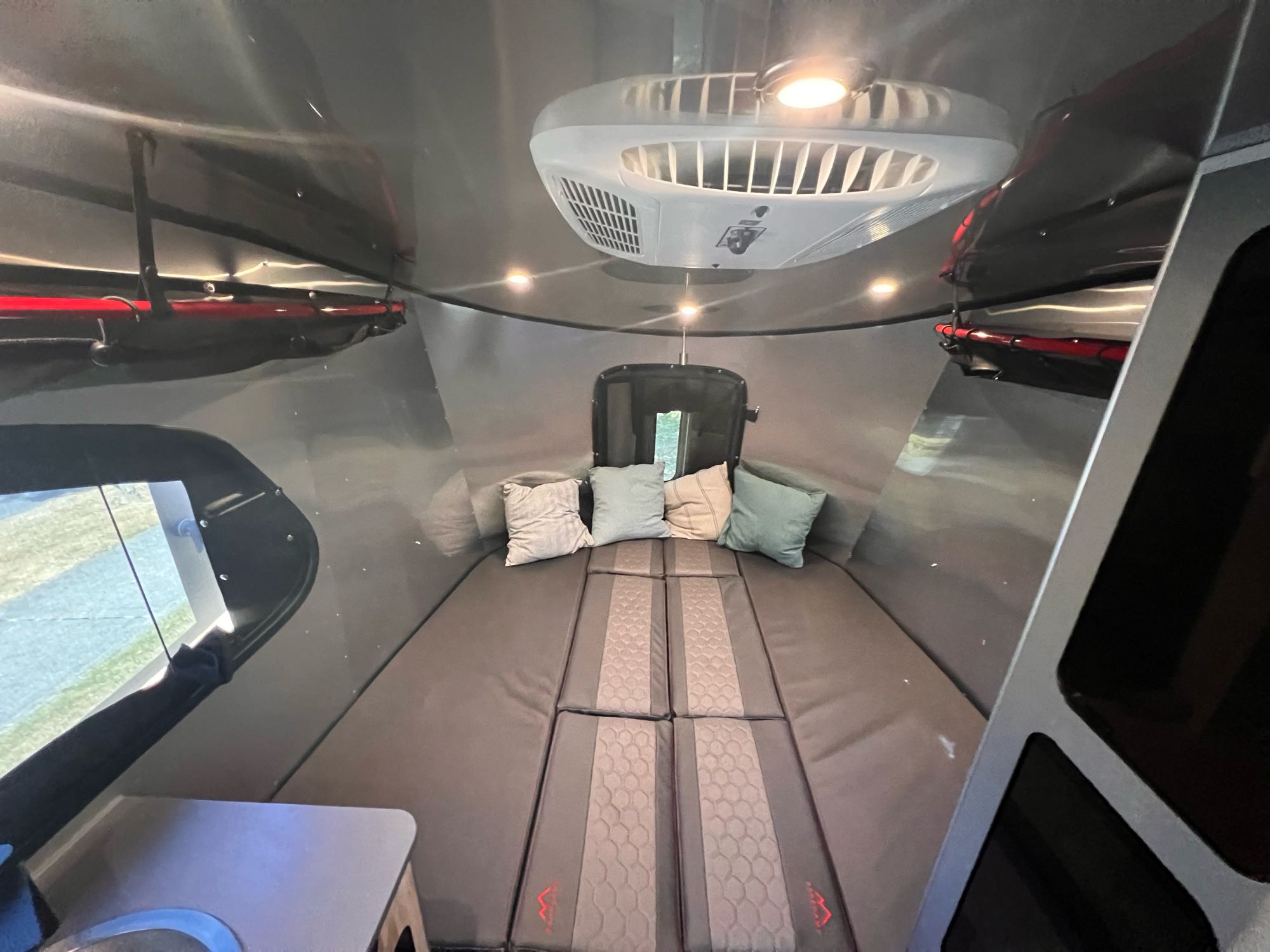 Cozy RV rental interior with a modular bed, overhead AC, and ambient lights. Ample storage & a view outside.. Airstream Basecamp 2022