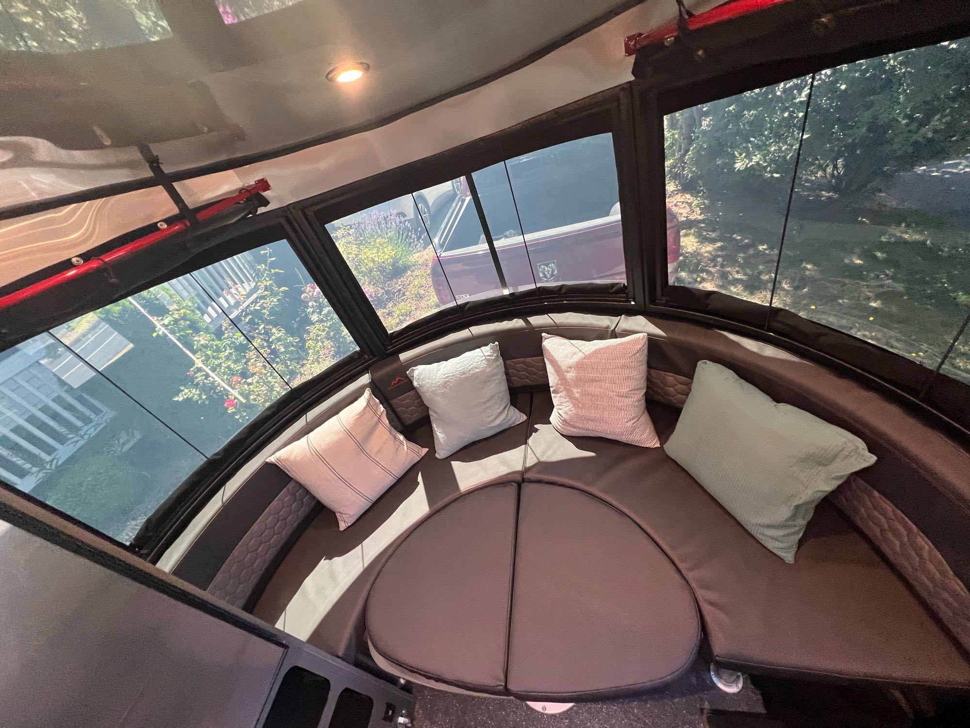 Cozy RV rental interior with curved lounge seating, throw pillows, and panoramic windows offering an outdoor view.. Airstream Basecamp 2022