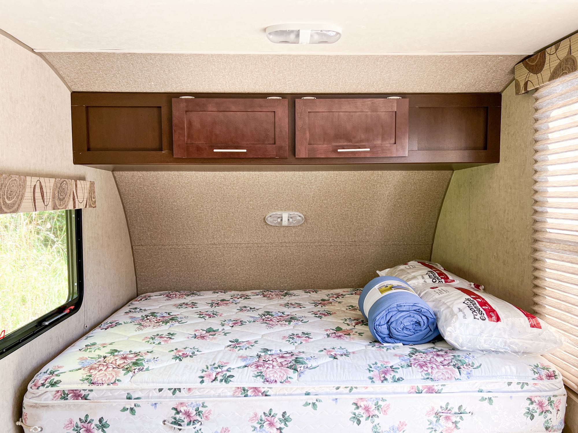 Cozy RV rental bedroom with floral mattress, overhead cabinets, and new bedding. Perfect for a restful trip.. Forest River Wolf Pup 2016