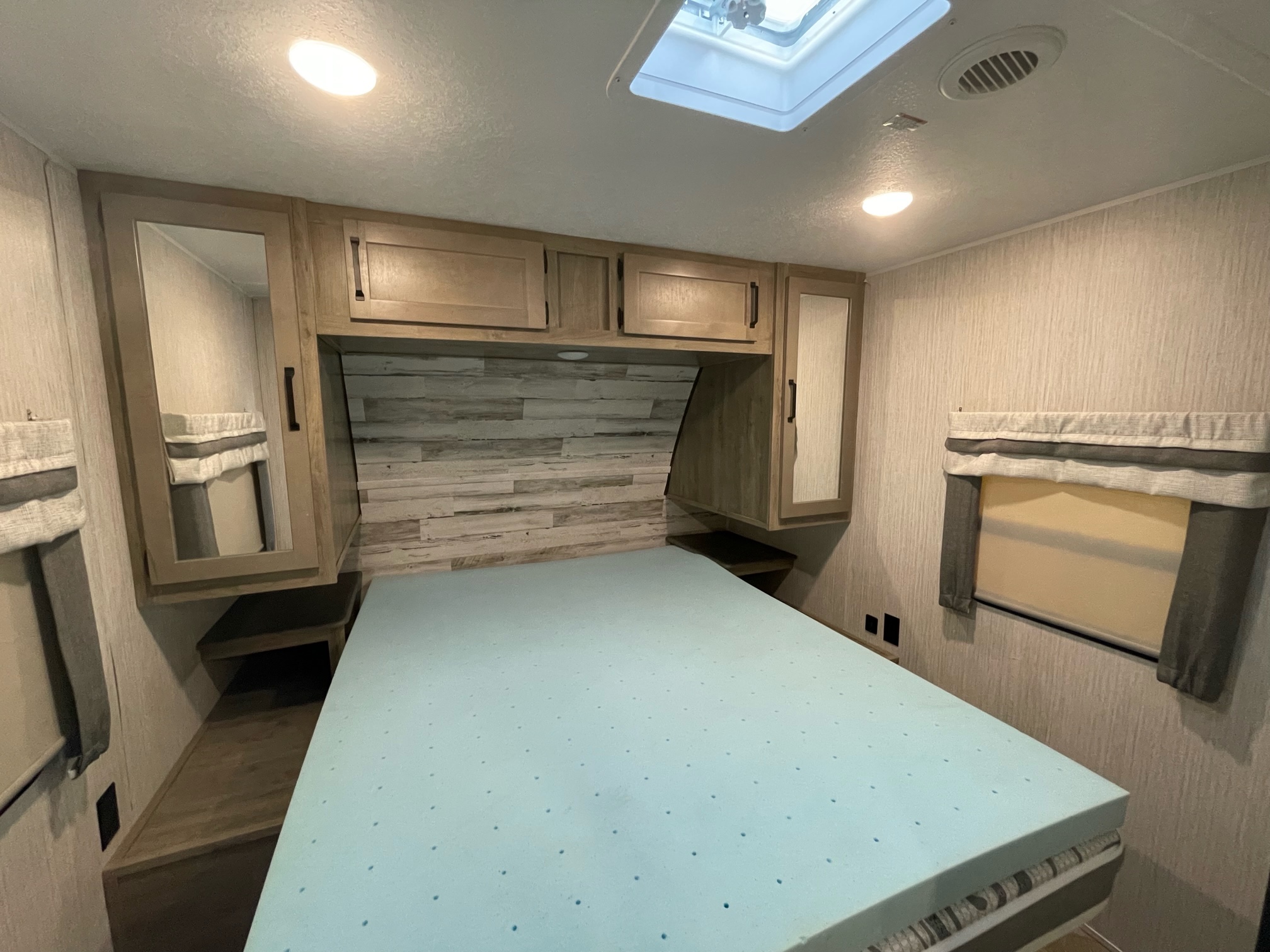 Cozy RV rental bedroom with memory foam topper, overhead storage, and skylight in a compact space.. Forest River Palomino Puma 2021