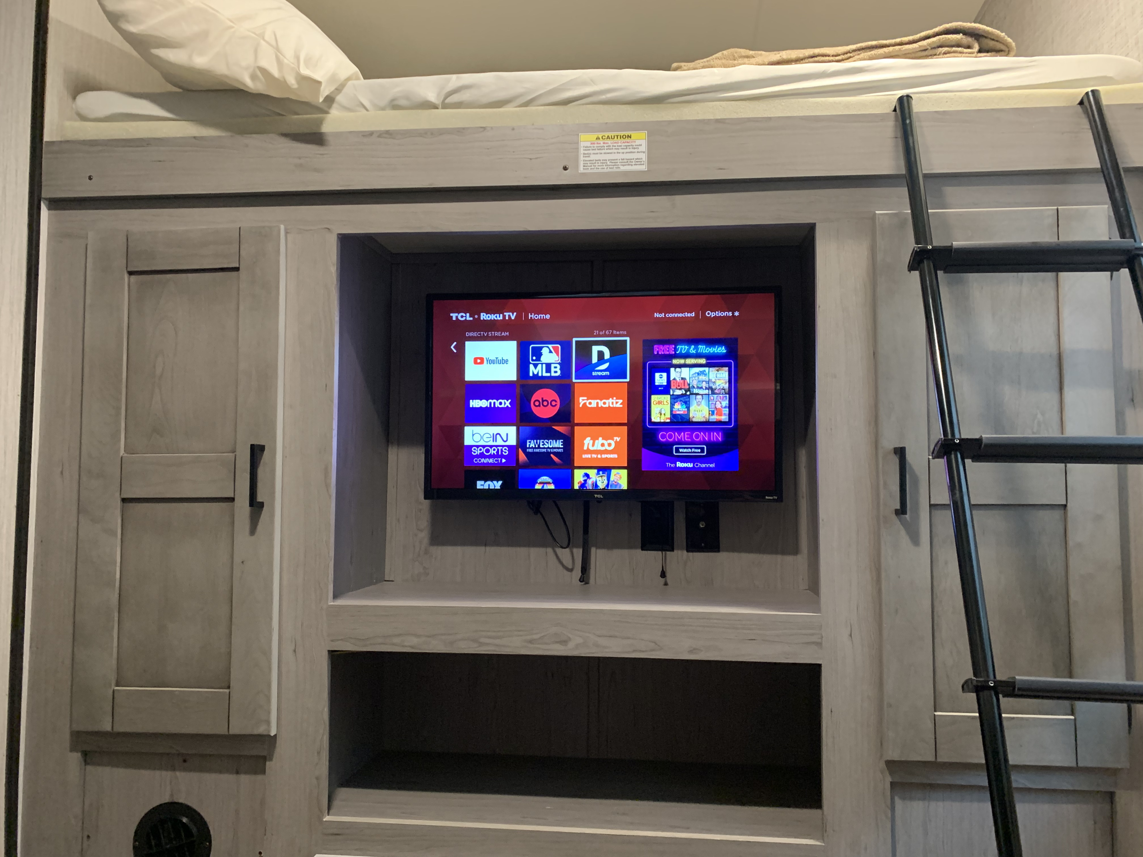 RV rental interior featuring a bunk bed with ladder and a smart TV showing streaming apps, perfect for family entertainment.. Heartland RVs Mallard 2021