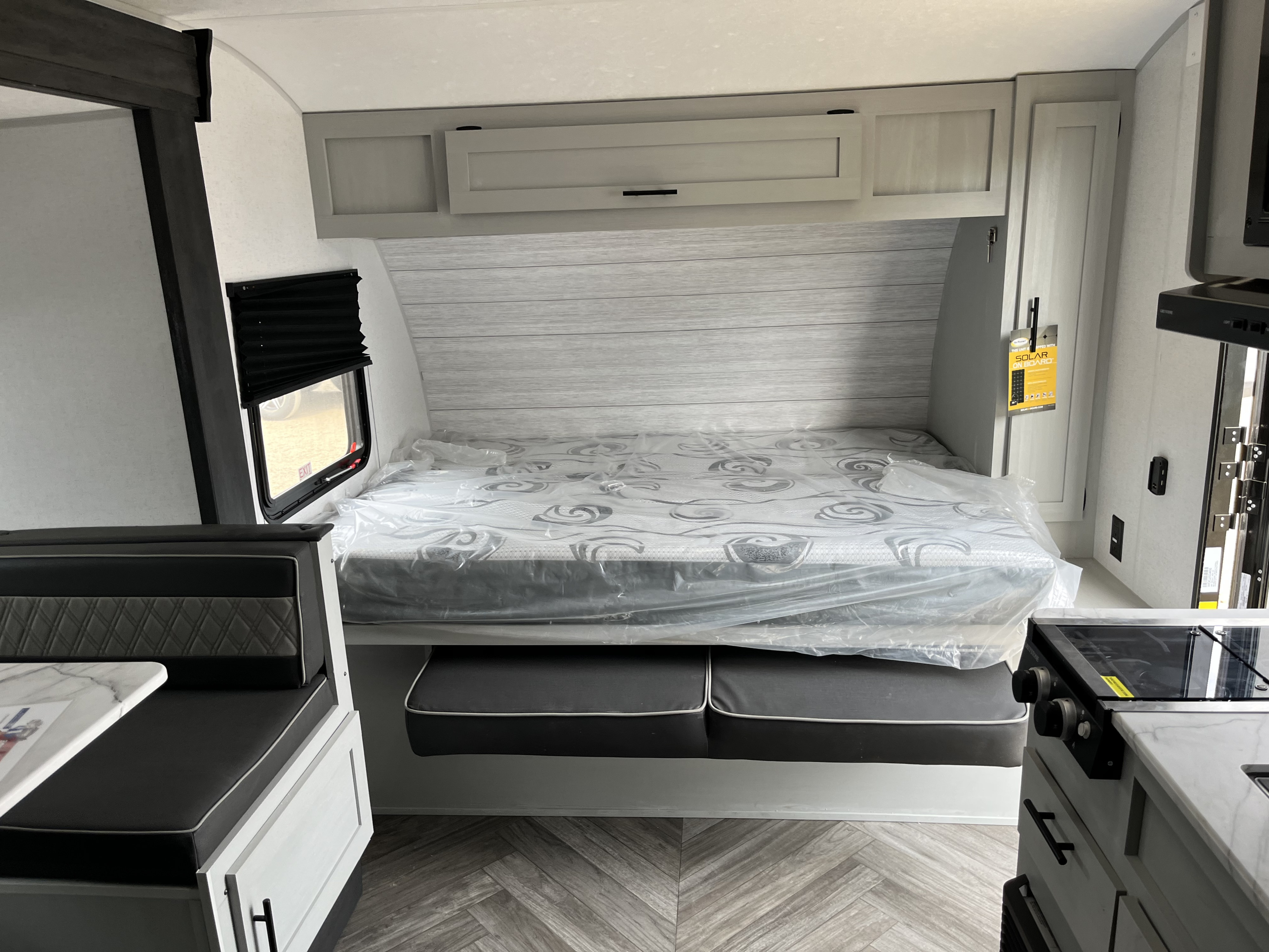 Clean RV rental interior: new bed (plastic-wrapped), dinette, & compact kitchen. Ready for your next adventure.. Forest River Wildwood FSX 2022