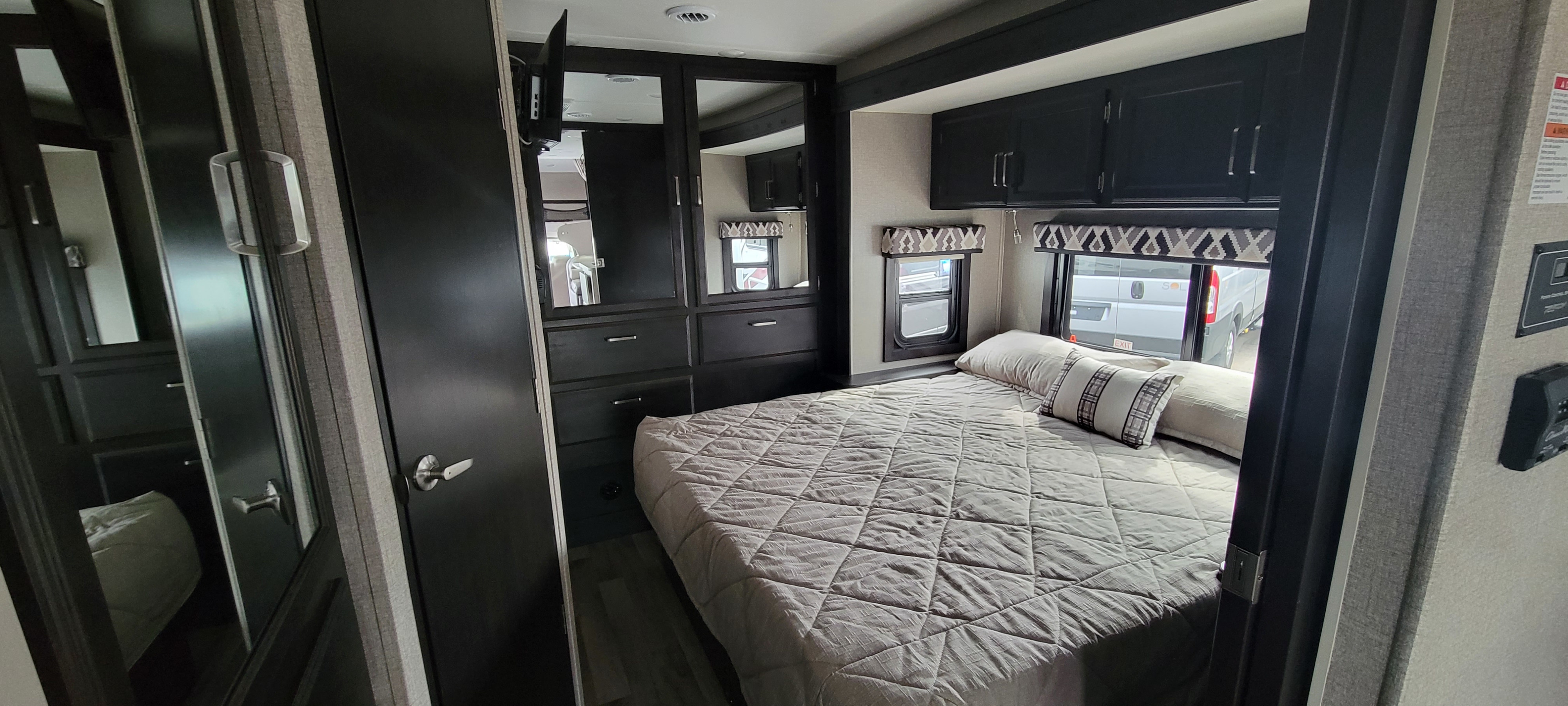 Step inside this modern RV rental bedroom, featuring a comfortable bed, mirrored closet, and ample storage for your adventures.. Jayco Greyhawk 2021