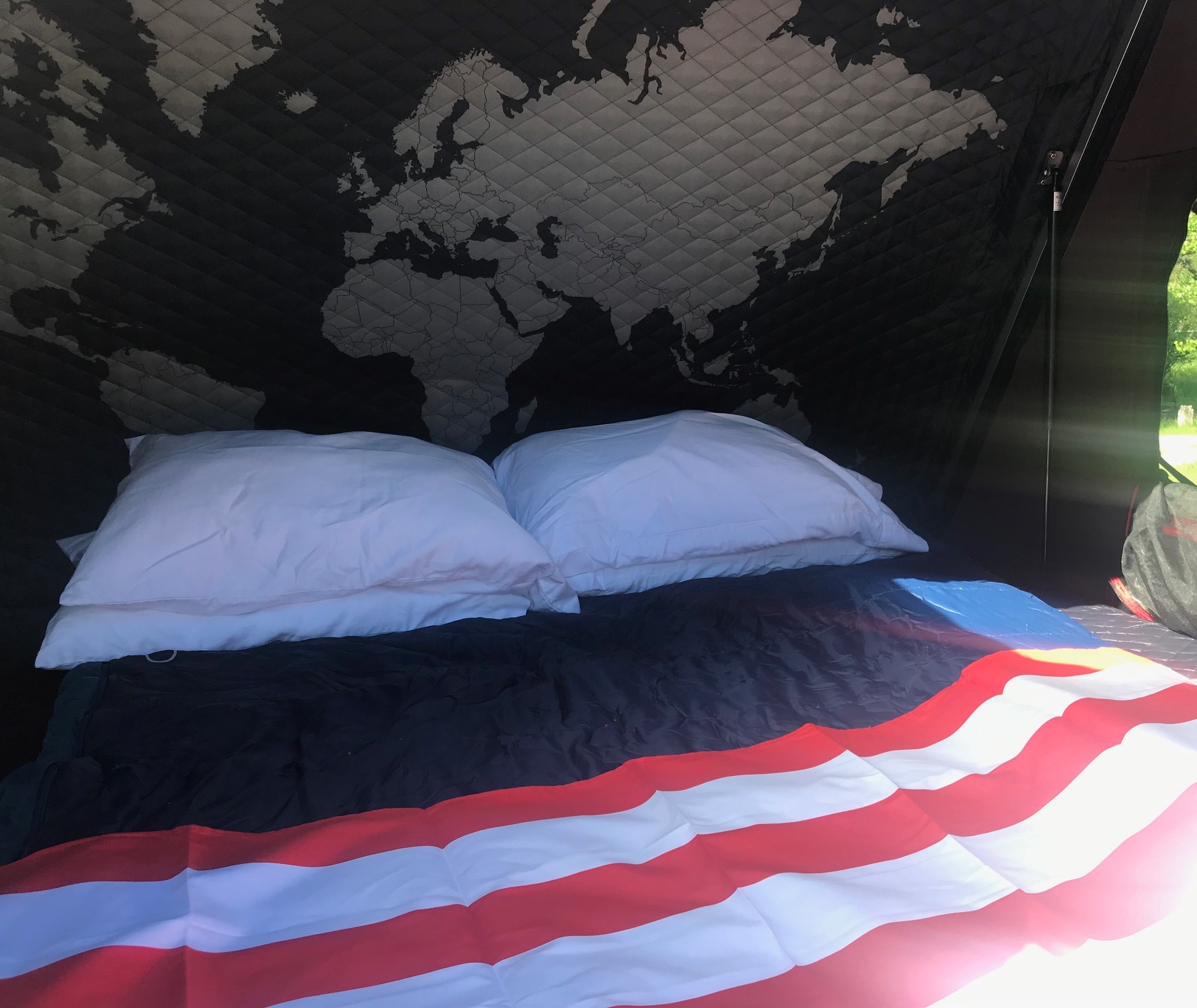 RV rental bed with white pillows, a patriotic blanket, & a quilted world map ceiling, perfect for travel.. Toyota 4Runner 2018