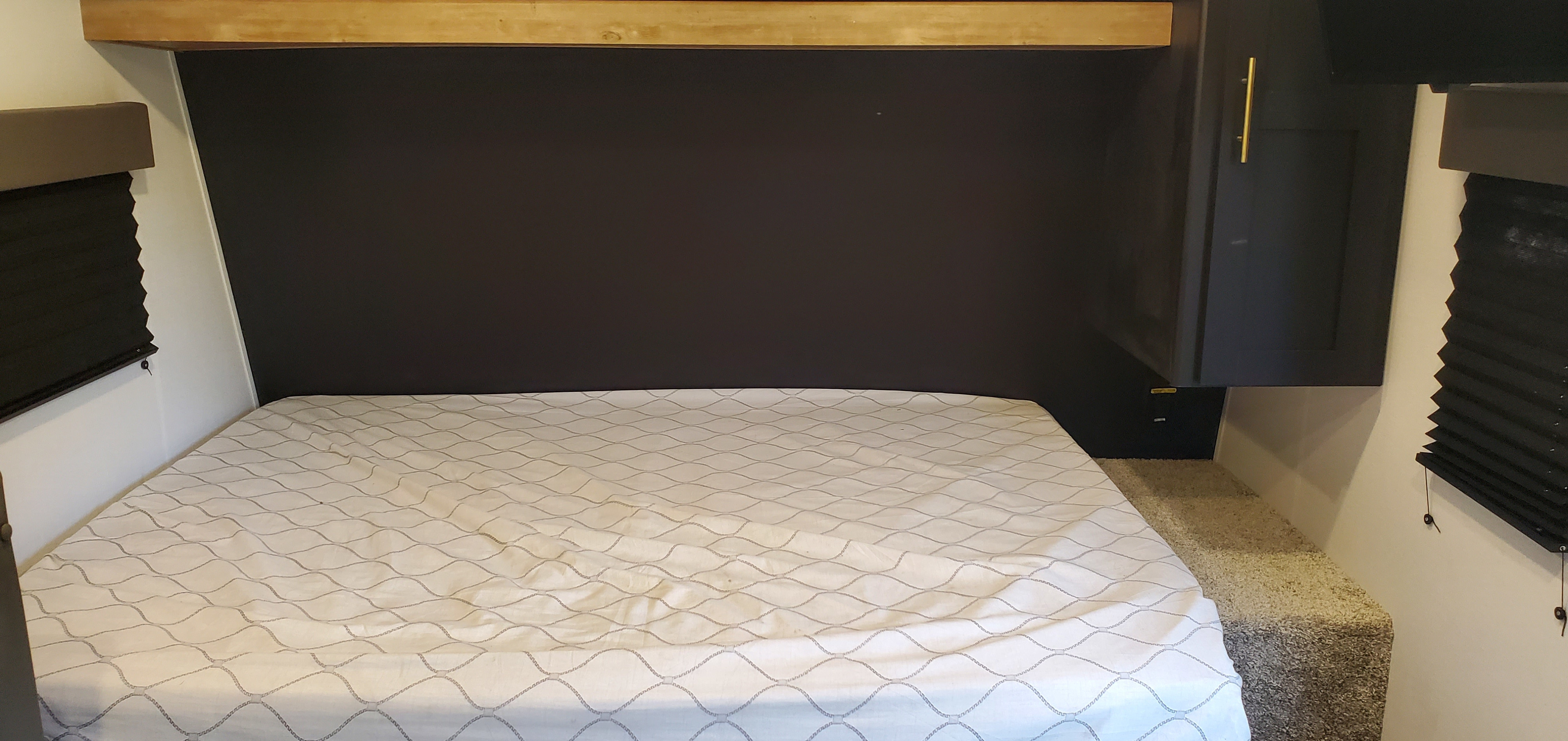 Cozy RV rental bedroom with comfortable mattress, overhead cabinet, and window blinds, perfect for your next trip.. Keystone RV Springdale 2022