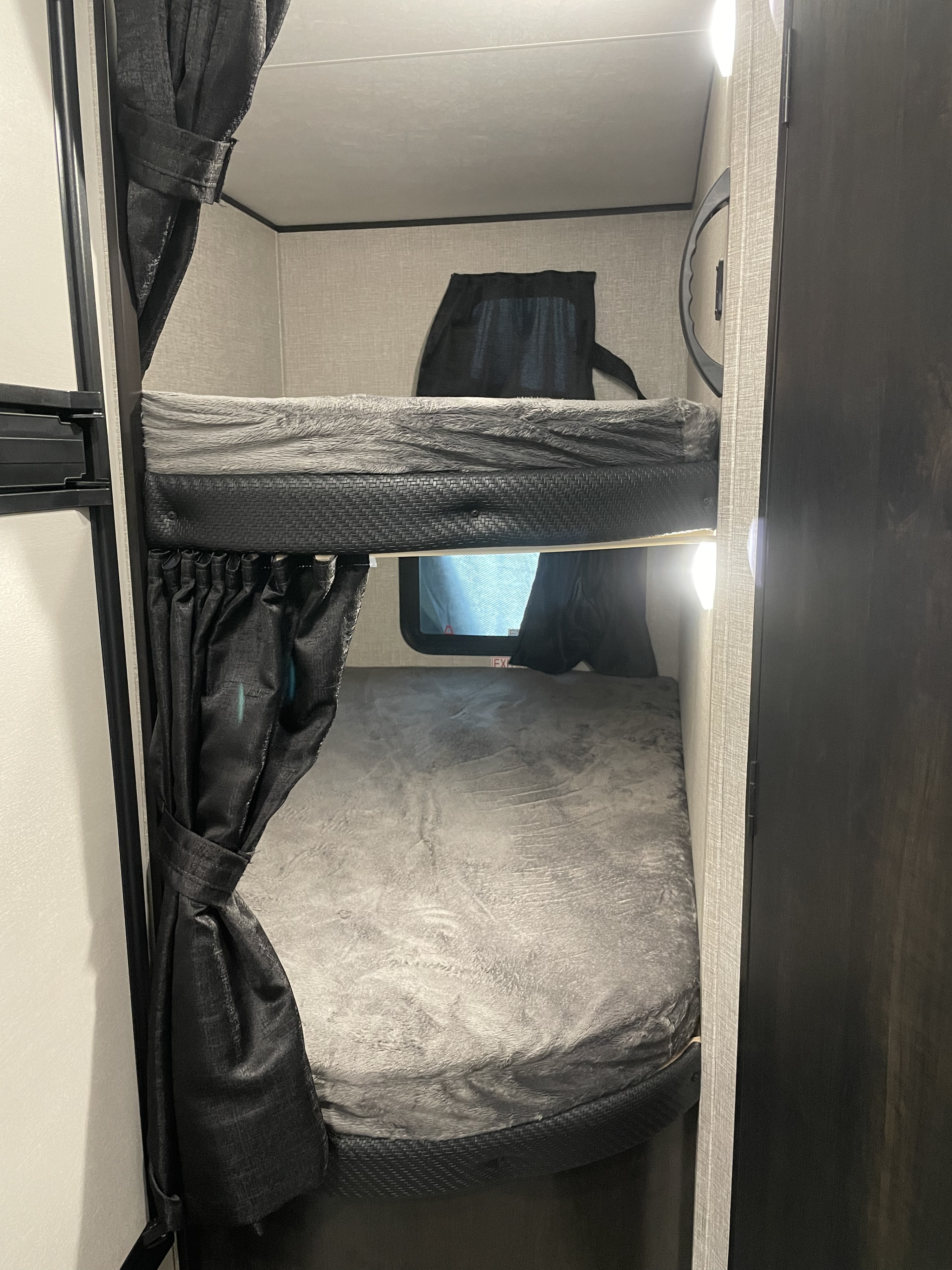 RV rental bunk beds: two cozy bunks with gray bedding & privacy curtains in a compact sleeping area.. Jayco Jay Flight SLX 2022