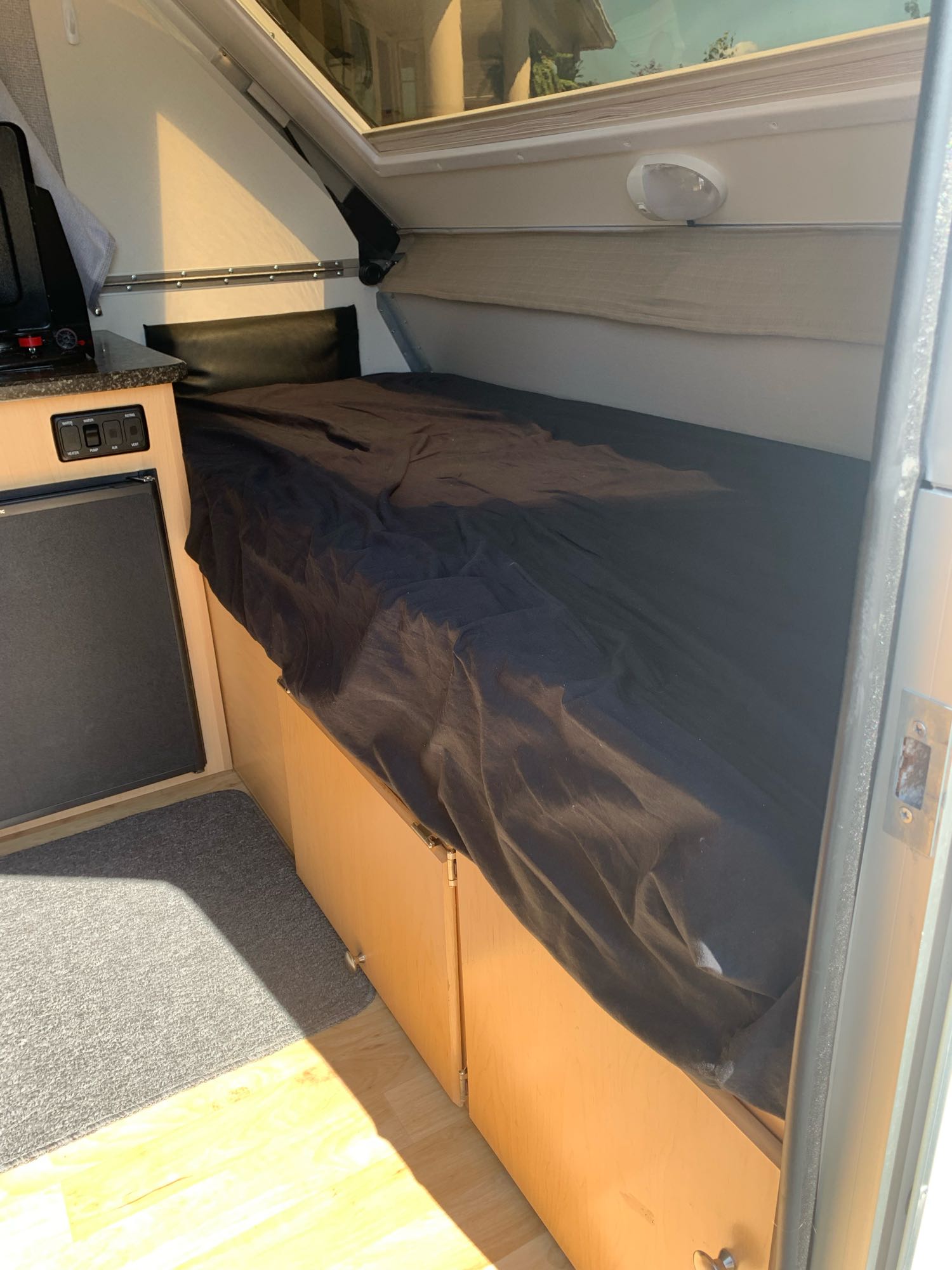 Cozy RV rental interior with a bed, small kitchen, and storage, perfect for compact travel.. A Liner A Liner Popup Trailer 2020