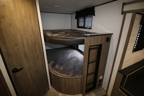 RV rental bunk beds. Cozy sleeping area in a travel trailer camper, visible wood interior & window with blinds.. Heartland RVs Pioneer 2022