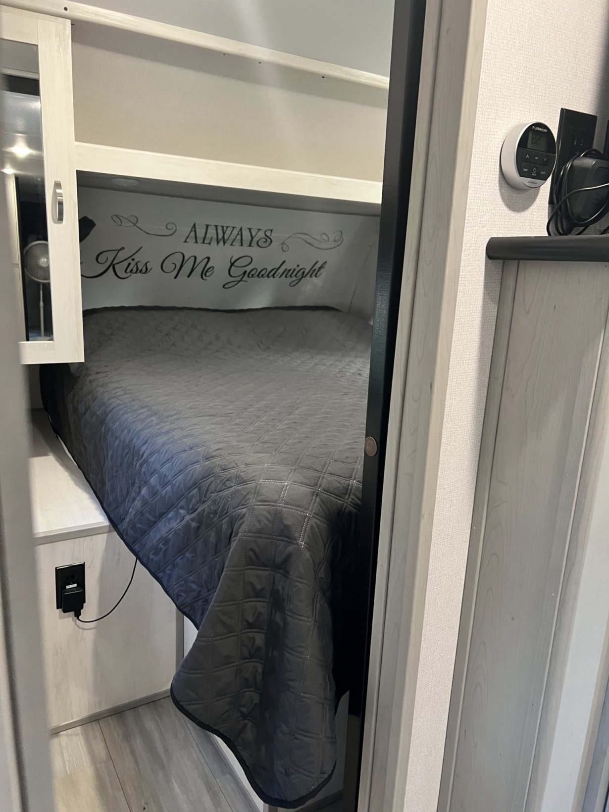 An RV rental's cozy bunk bed, featuring "Always Kiss Me Goodnight" wall art and a thermostat nearby.. PrimeTime 31BHD 2021