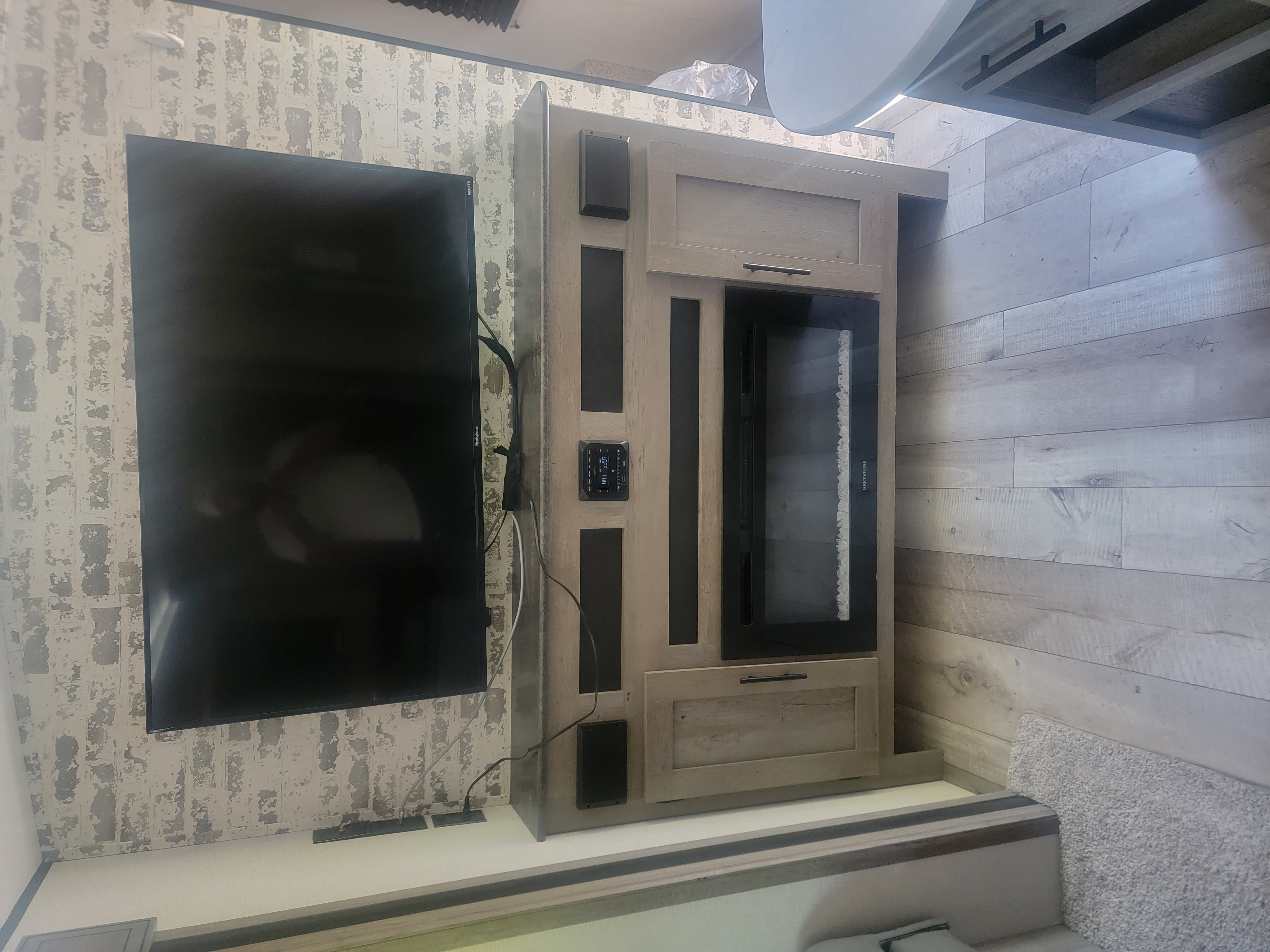 Modern RV rental interior with a wall-mounted TV, electric fireplace, control panel, and integrated speakers.. Keystone RV Springdale 2021