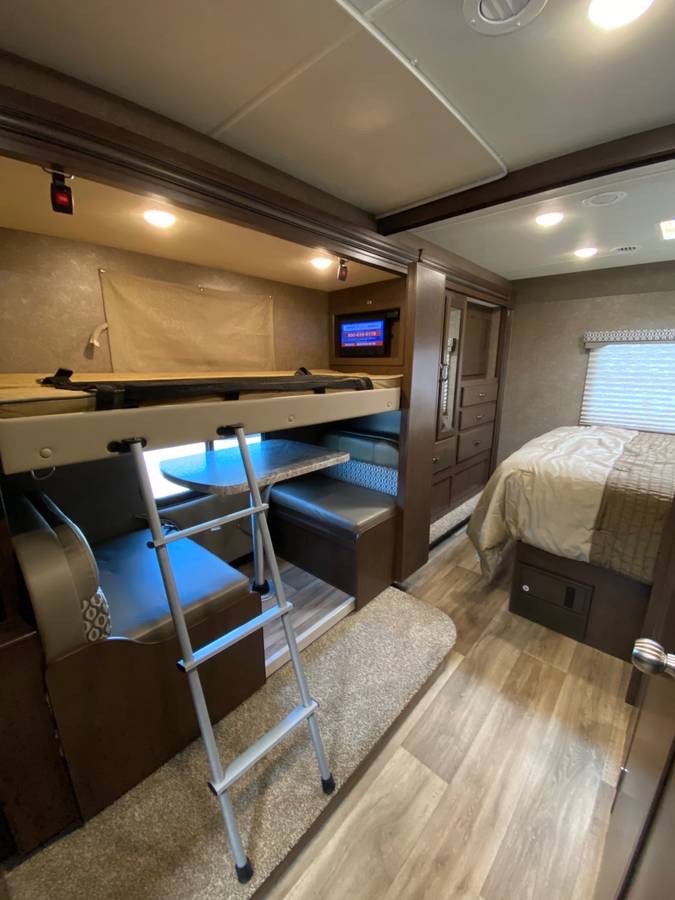 RV rental interior: bunk beds with ladder, lower dinette, and master bed section. Ample living and sleeping space for travelers.. Thor Freedom Elite 2020