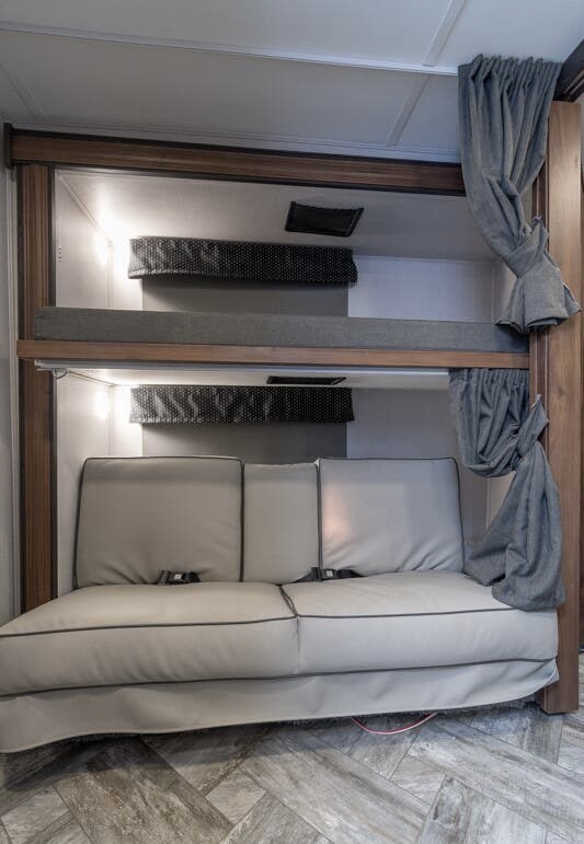 RV rental interior: two bunk beds with safety nets & lights, above a sofa with seatbelts. Efficient sleeping/living space.. Forester LE 2022