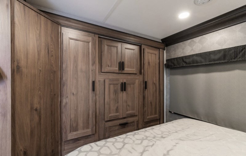 RV rental bedroom featuring built-in wooden wardrobe and storage cabinets over a comfy bed, maximizing space.. Forester LE 2022