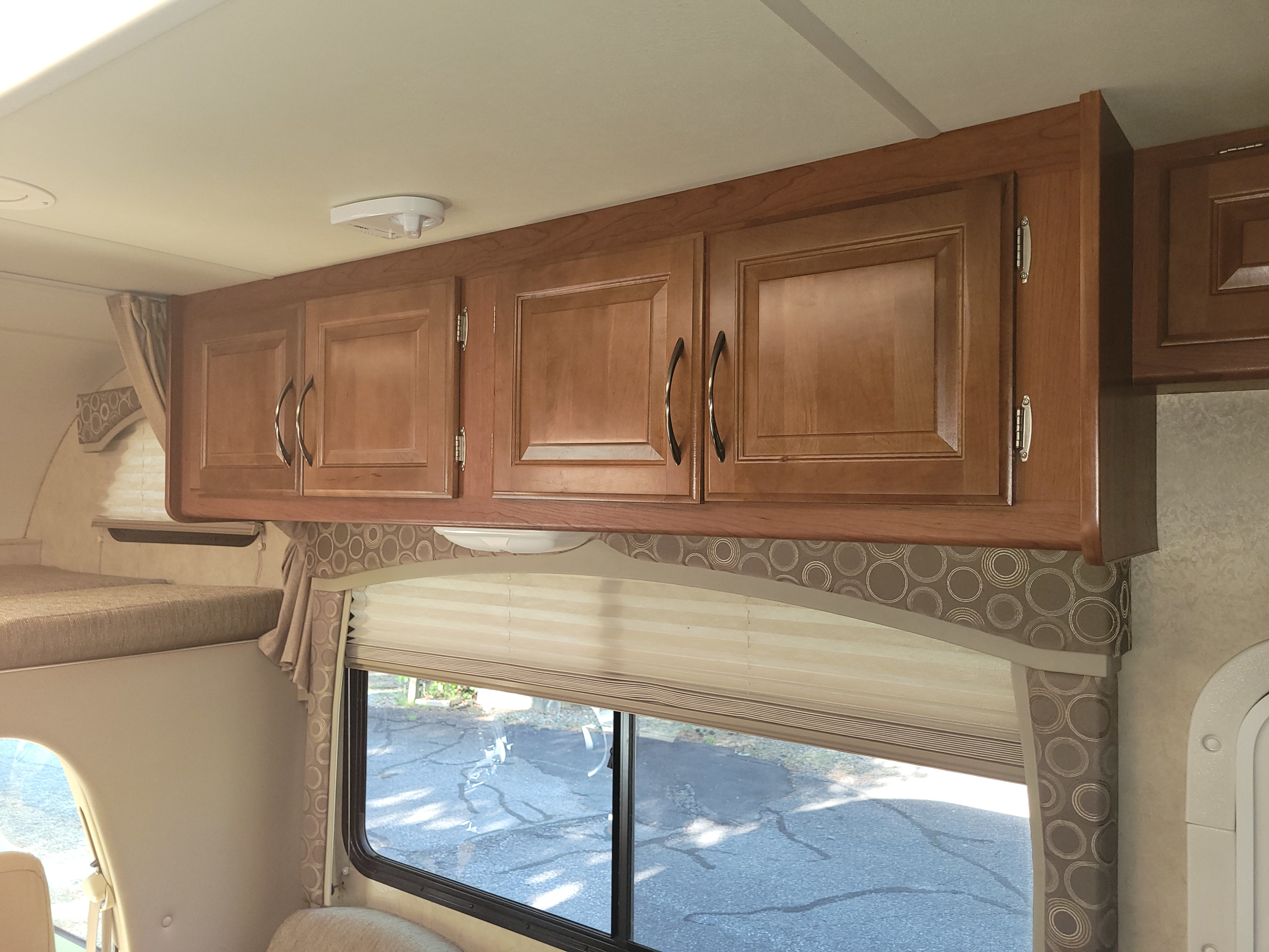 Explore this RV rental's interior: light wood overhead cabinets, a window with striped blinds, and a forward bunk area.. Thor Chateau 2012