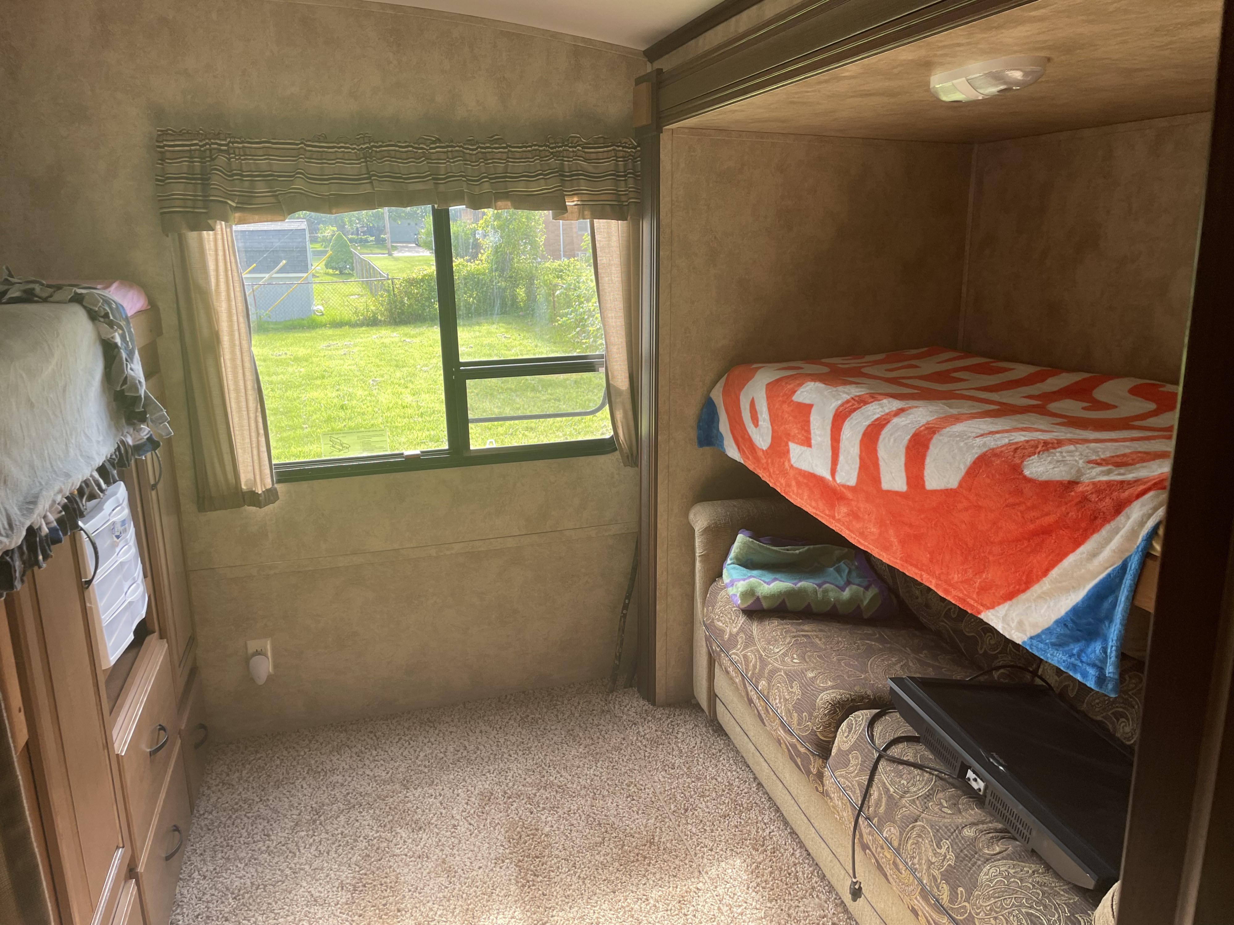 This rv rental offers cozy bunk beds, a large window with a view, cabinetry, and a TV for a comfortable interior.. Keystone RV Outback 2013