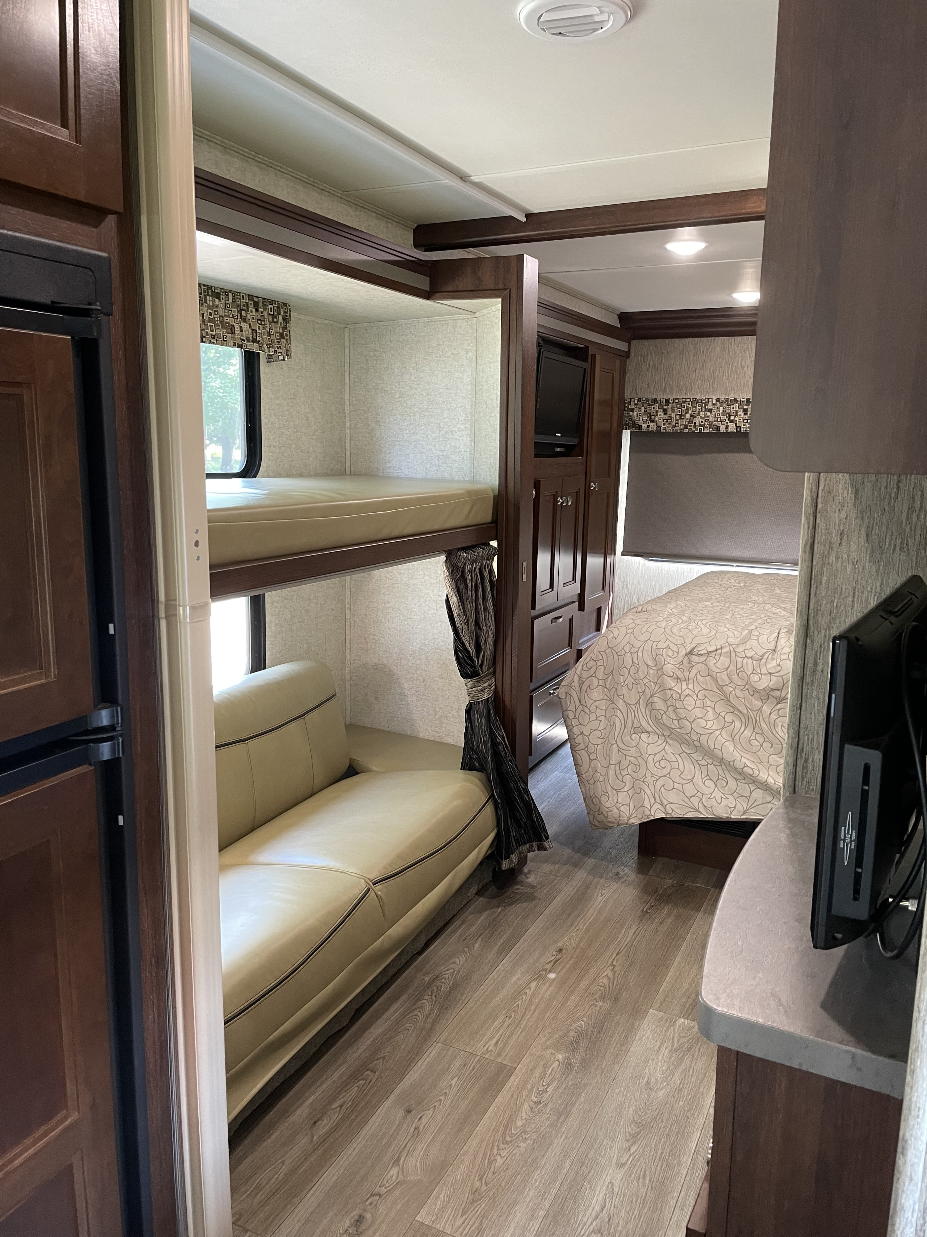 Explore a comfortable RV rental interior: bunk beds, a spacious lounge area with a couch, and a private rear bedroom. Modern amenities included.. Forest River Sunseeker 2017