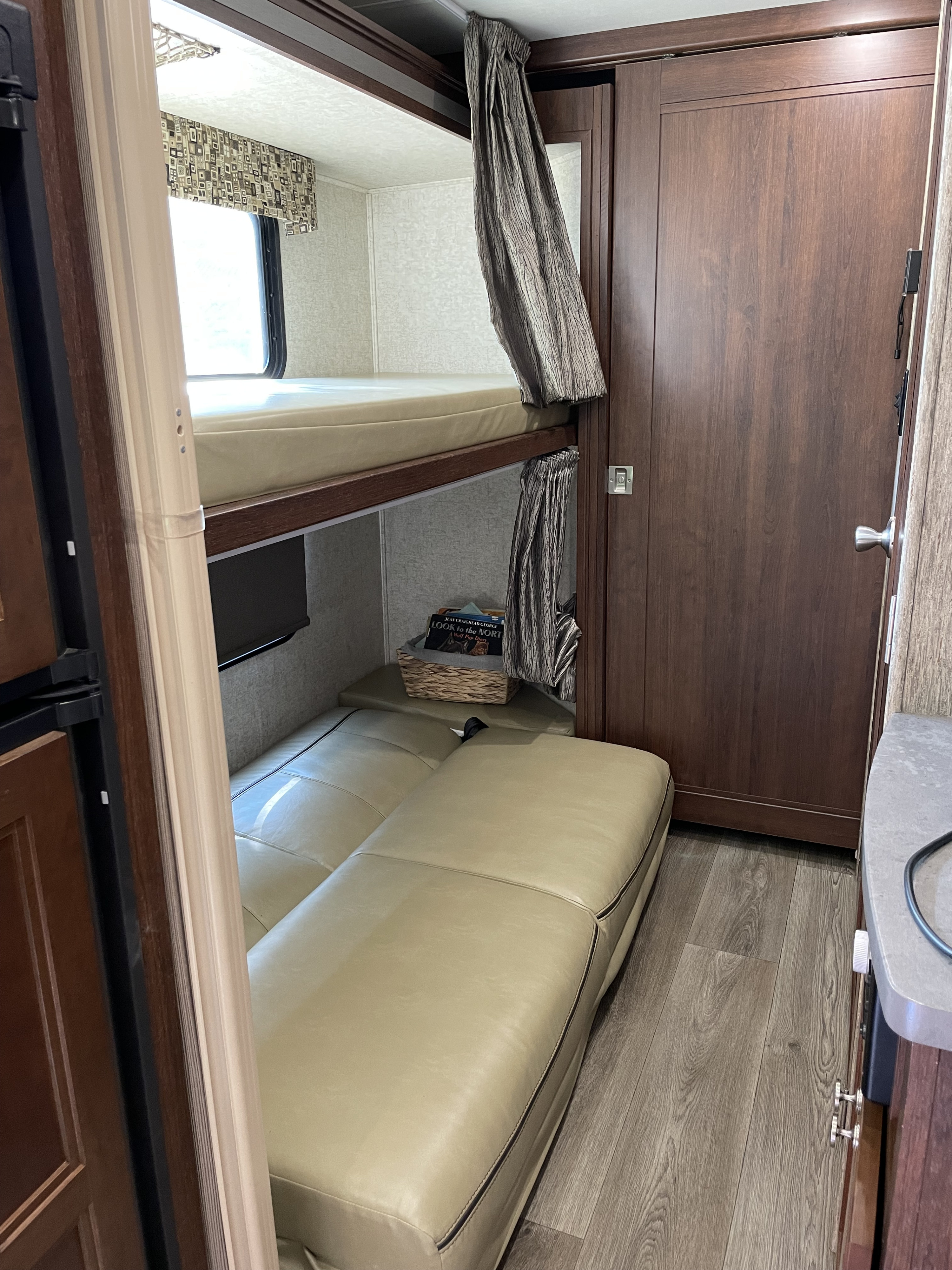 Explore this cozy RV rental interior featuring comfortable bunk beds and a convertible sleeper sofa, perfect for compact travel living.. Forest River Sunseeker 2017