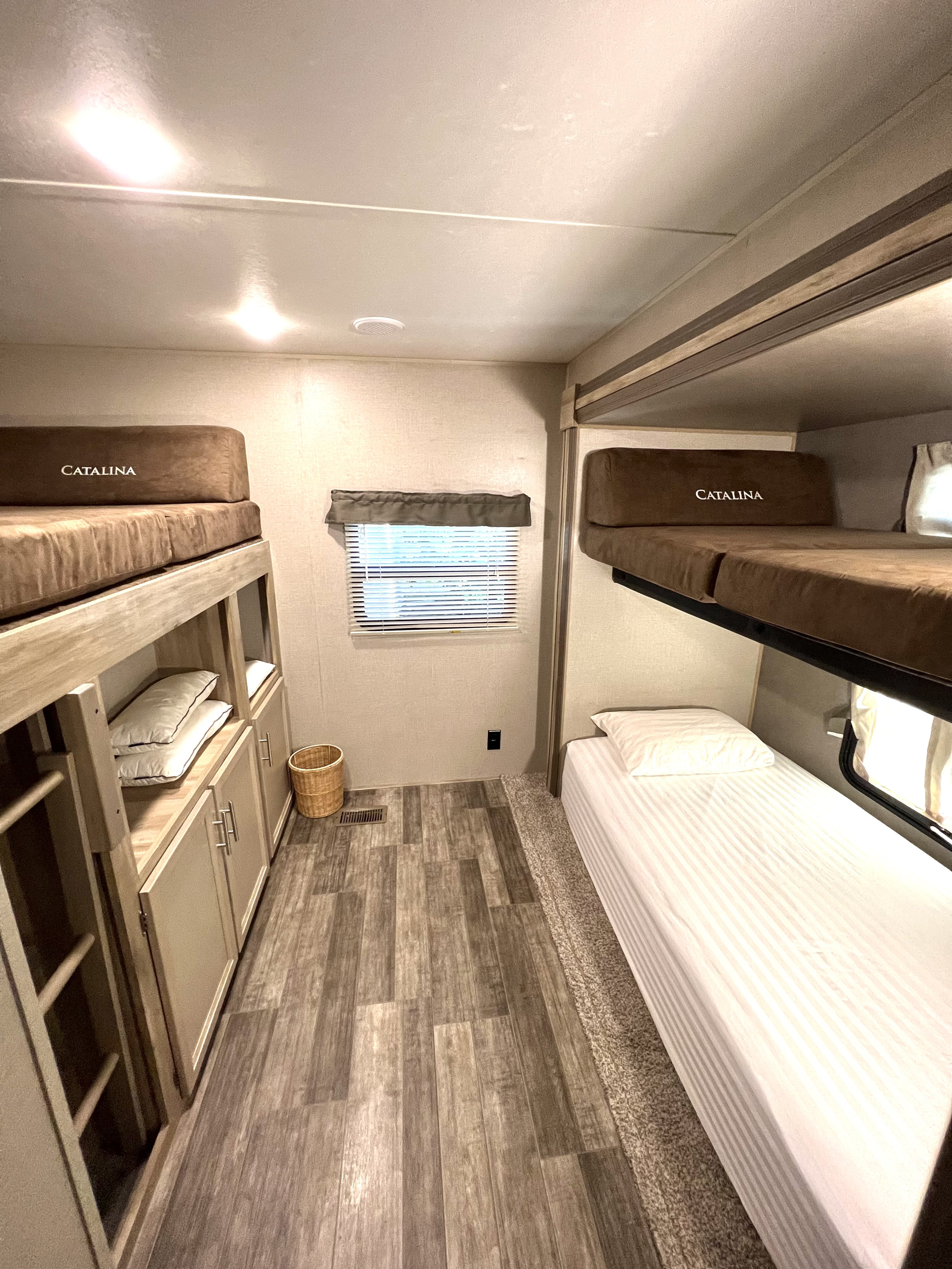 This RV rental bunk room offers comfort with four bunks, 'Catalina' branding, integrated storage, and modern wood-look floors.. Catalina Legacy 343BHTS 2021