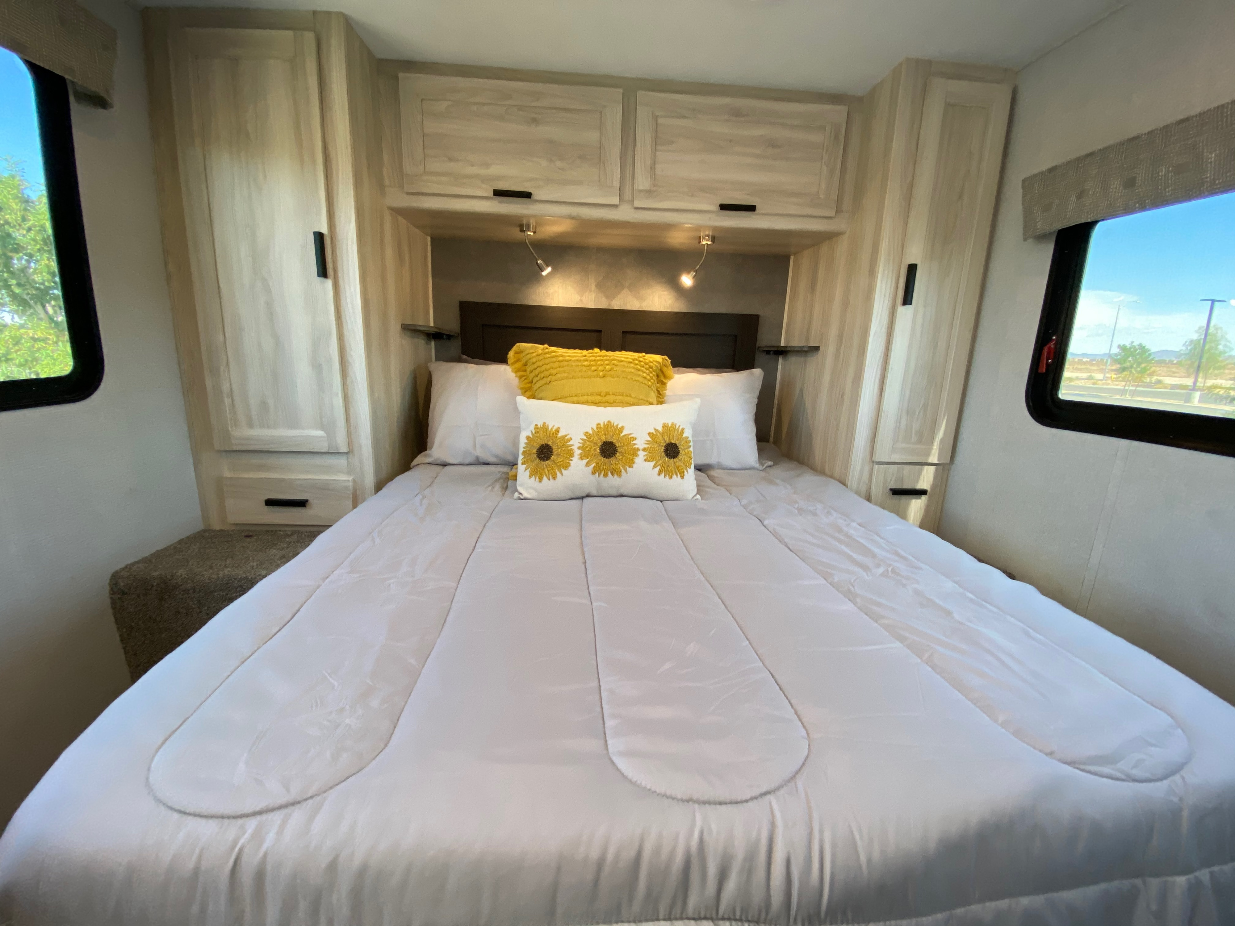 Comfortable RV rental bedroom with light wood cabinets, cozy bedding, and bright sunflower pillows.. Forest River Sunseeker LE 2022