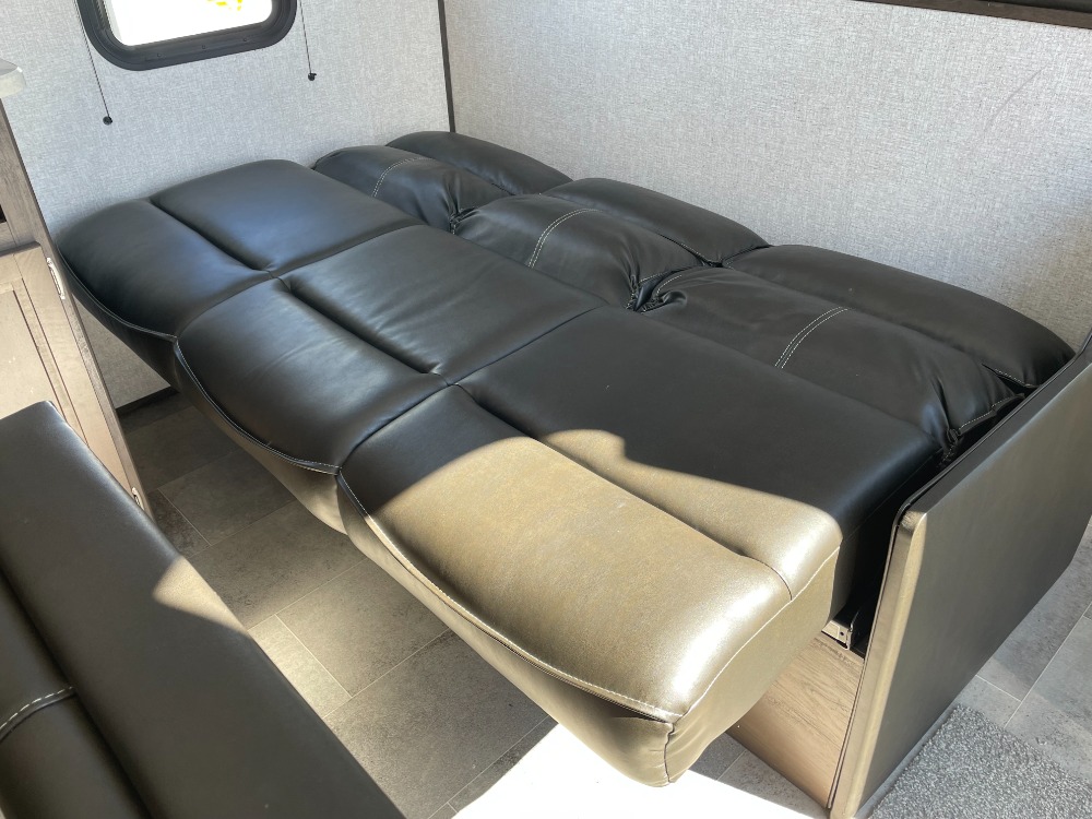 Inside an RV rental, a multi-section black leather sofa converts to a bed, offering versatile seating and sleeping.. Dutchmen Coleman Lantern LT 2022