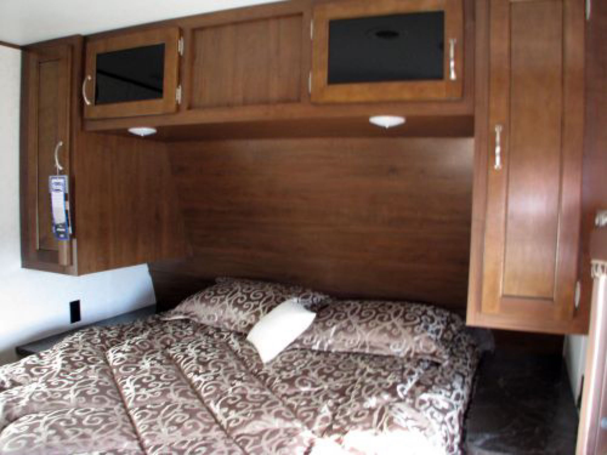 RV rental bedroom: a cozy interior with patterned bedding, wood cabinets, and integrated lighting for comfortable stays.. Jayco Jay Flight 2017