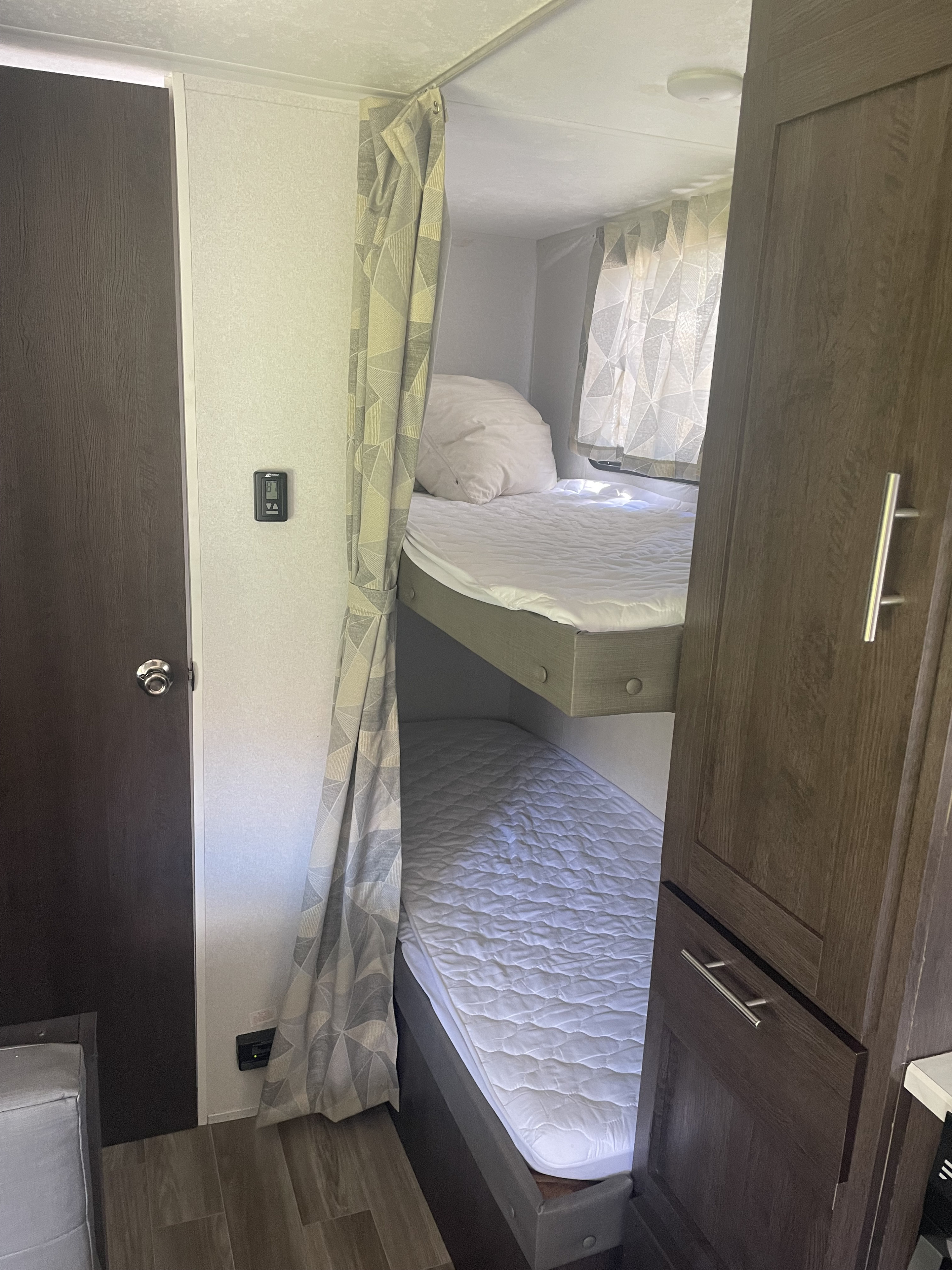 RV rental interior showing comfortable bunk beds with white bedding and a privacy curtain.. Forest River Cruise Lite 2019