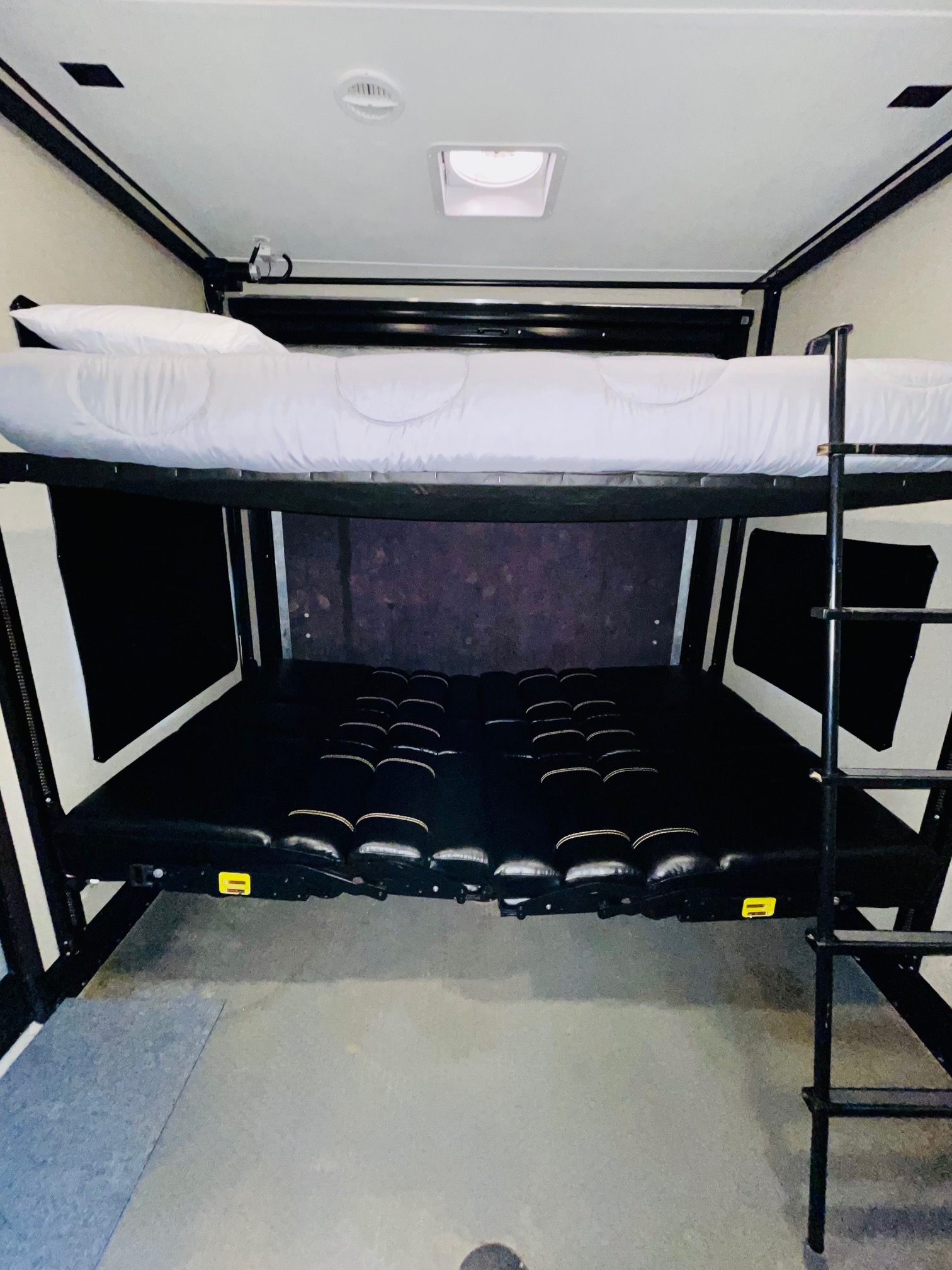 Inside an RV rental: a bunk bed system with a made-up top bunk and convertible seating below.. Keystone Carbon 2017