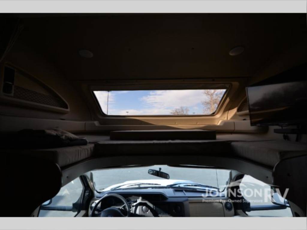 Spacious RV rental interior with a comfy cab-over bunk bed, large skylight, and front cabin view. Perfect for travel!. Entegra Coach Odyssey 2019