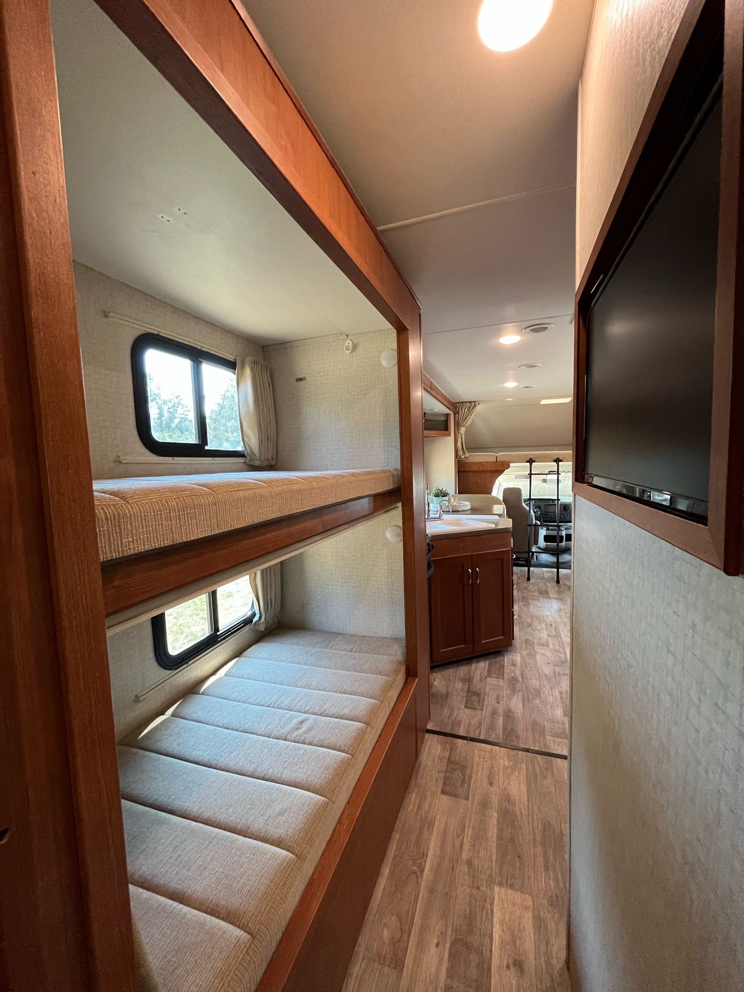 View from bunks inside an RV rental, showing the cozy sleeping area, kitchen, and front cockpit, ideal for road trips.. Winnebago Minnie Winnie 2017