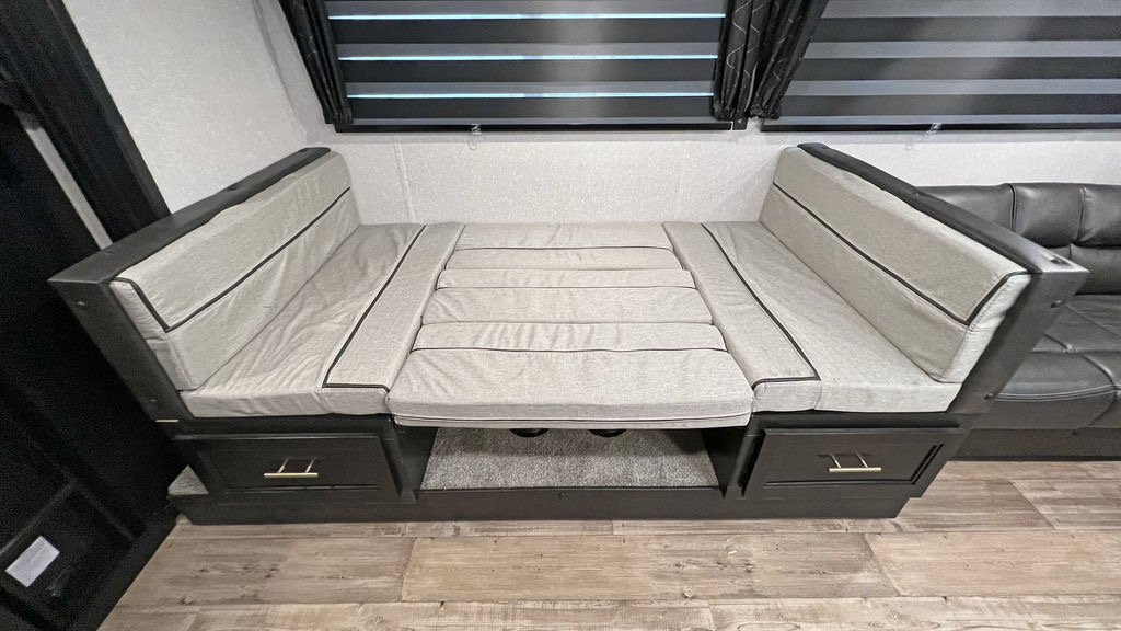 Comfortable RV rental dinette bed conversion with light gray cushions, storage drawers, and blinds for privacy.. Forest River Cherokee Grey Wolf 2022