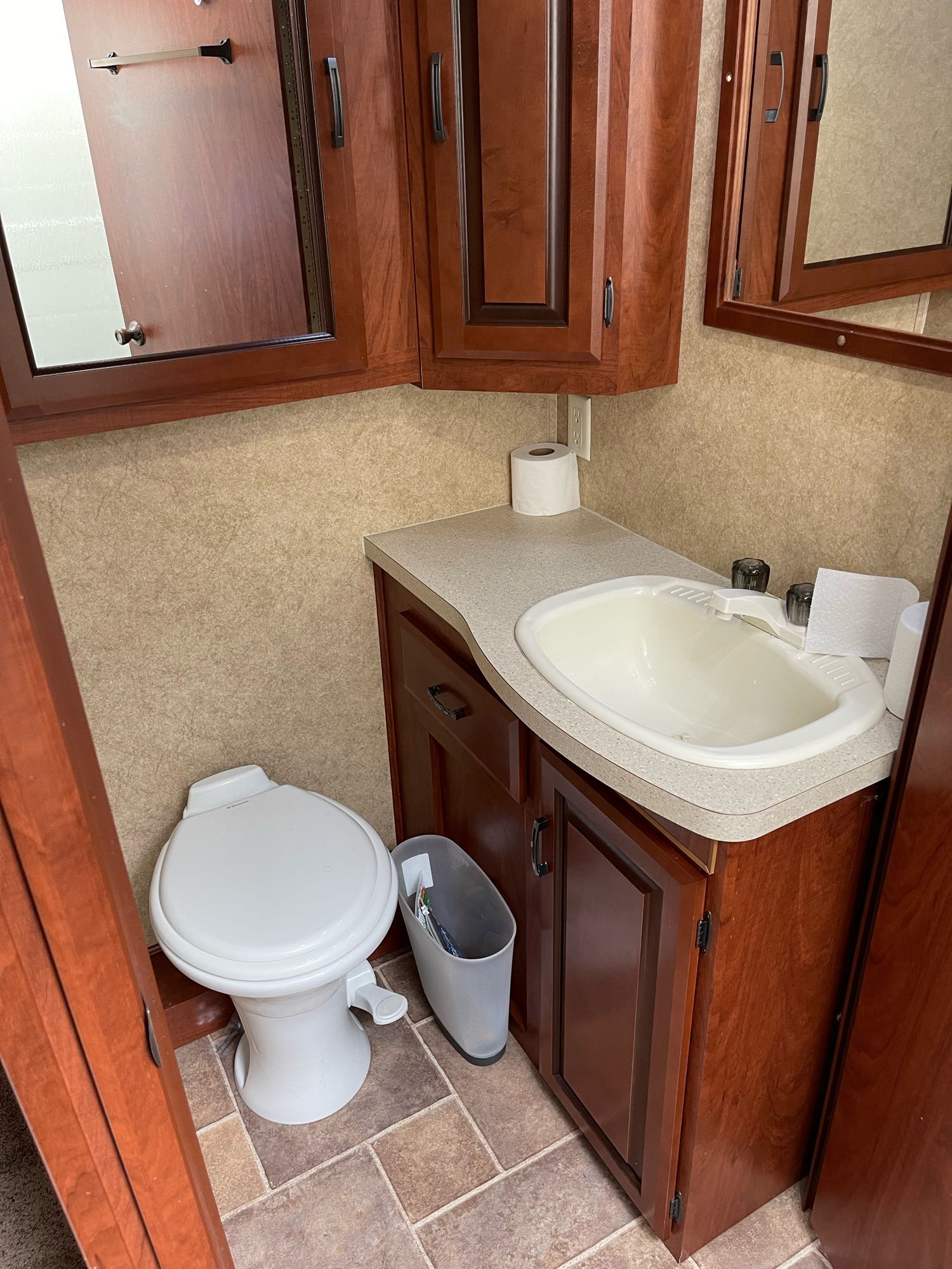 RV rental bathroom: A compact space with white toilet, sink, mirror, and cherry-toned cabinets. Ideal for travel.. Forest River Sunseeker 2013