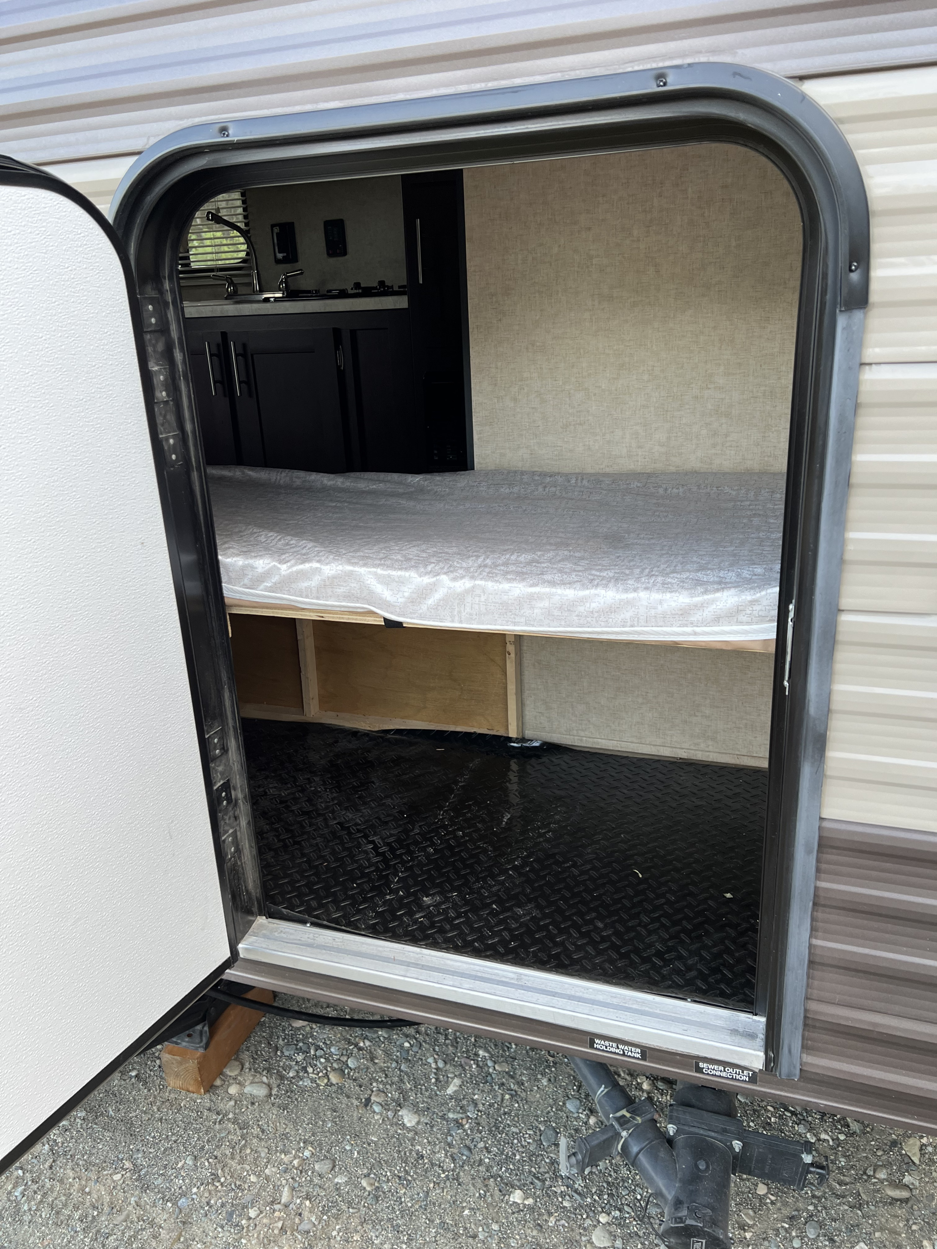 Inside an RV rental: view through the open door showing the sleeping area, kitchen, and black diamond plate floor.. Forest River Cherokee Wolf Pup 2018