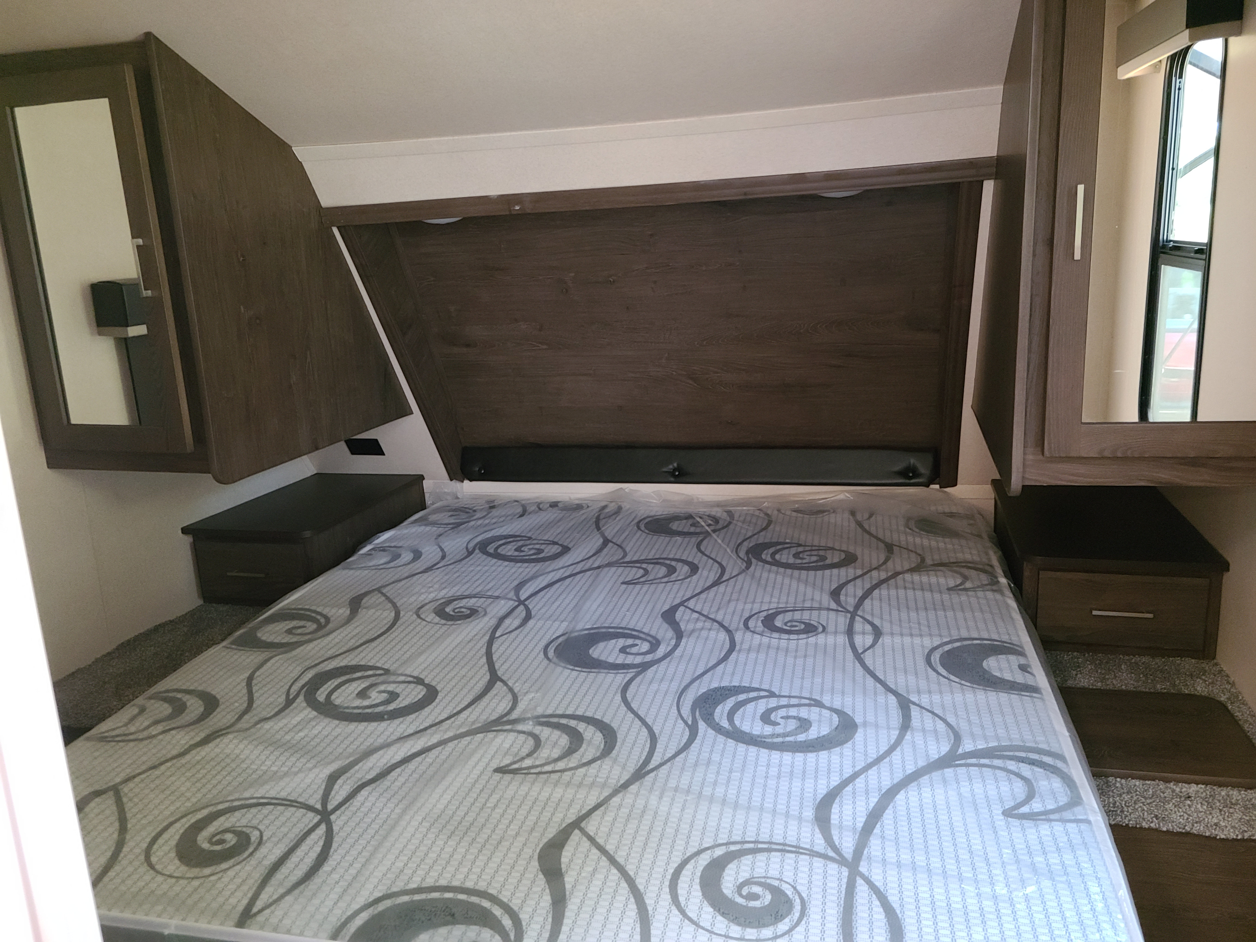 This RV rental bedroom features a comfy bed, dark wood cabinets, and integrated storage, showcasing a compact yet functional space.. Forest River Salem Hemisphere GLX 2019