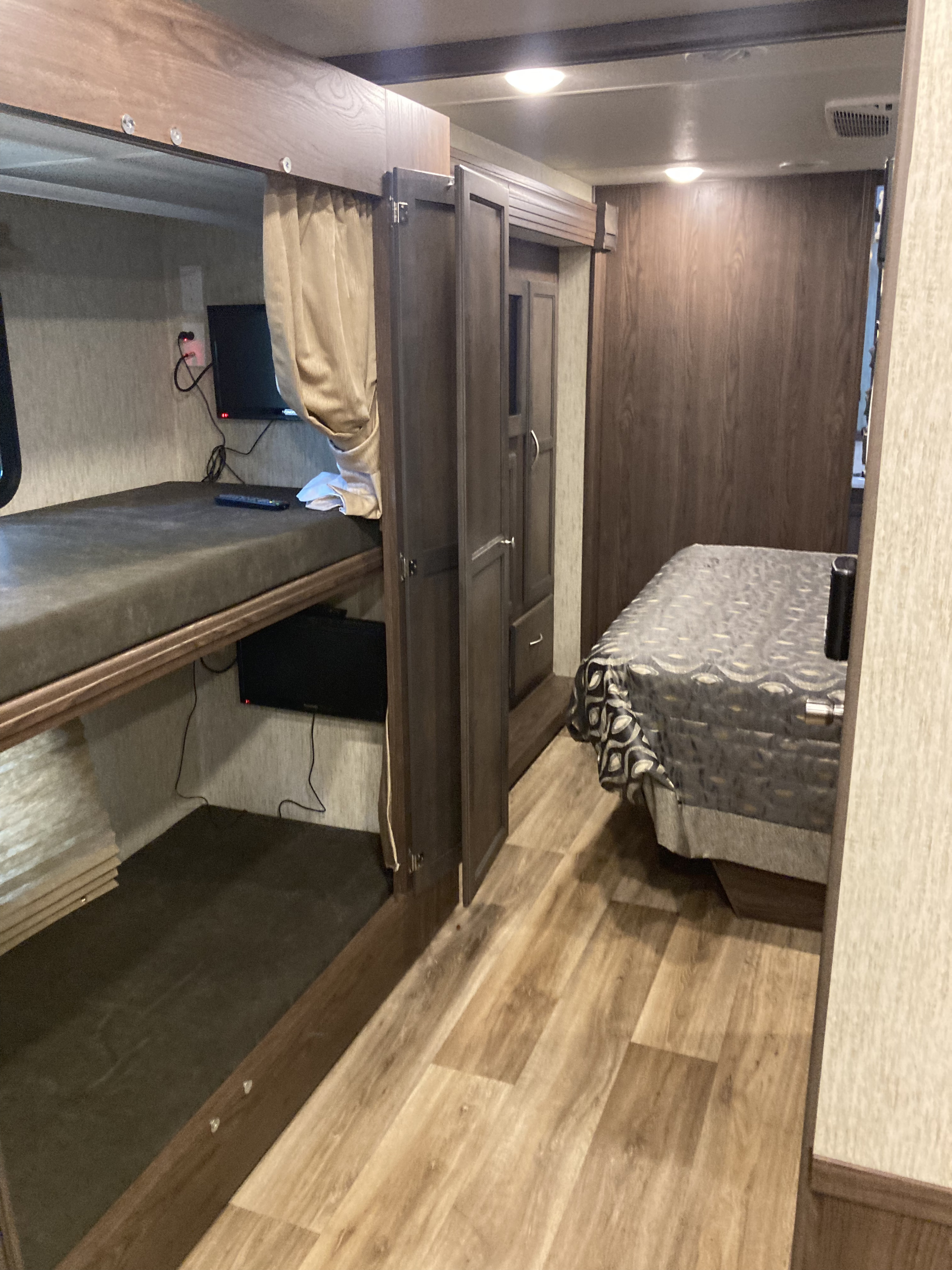 This RV rental interior showcases cozy bunk beds, a practical wardrobe, and a comfy main bedroom area for travel.. Forest River Coachmen Mirada 2019